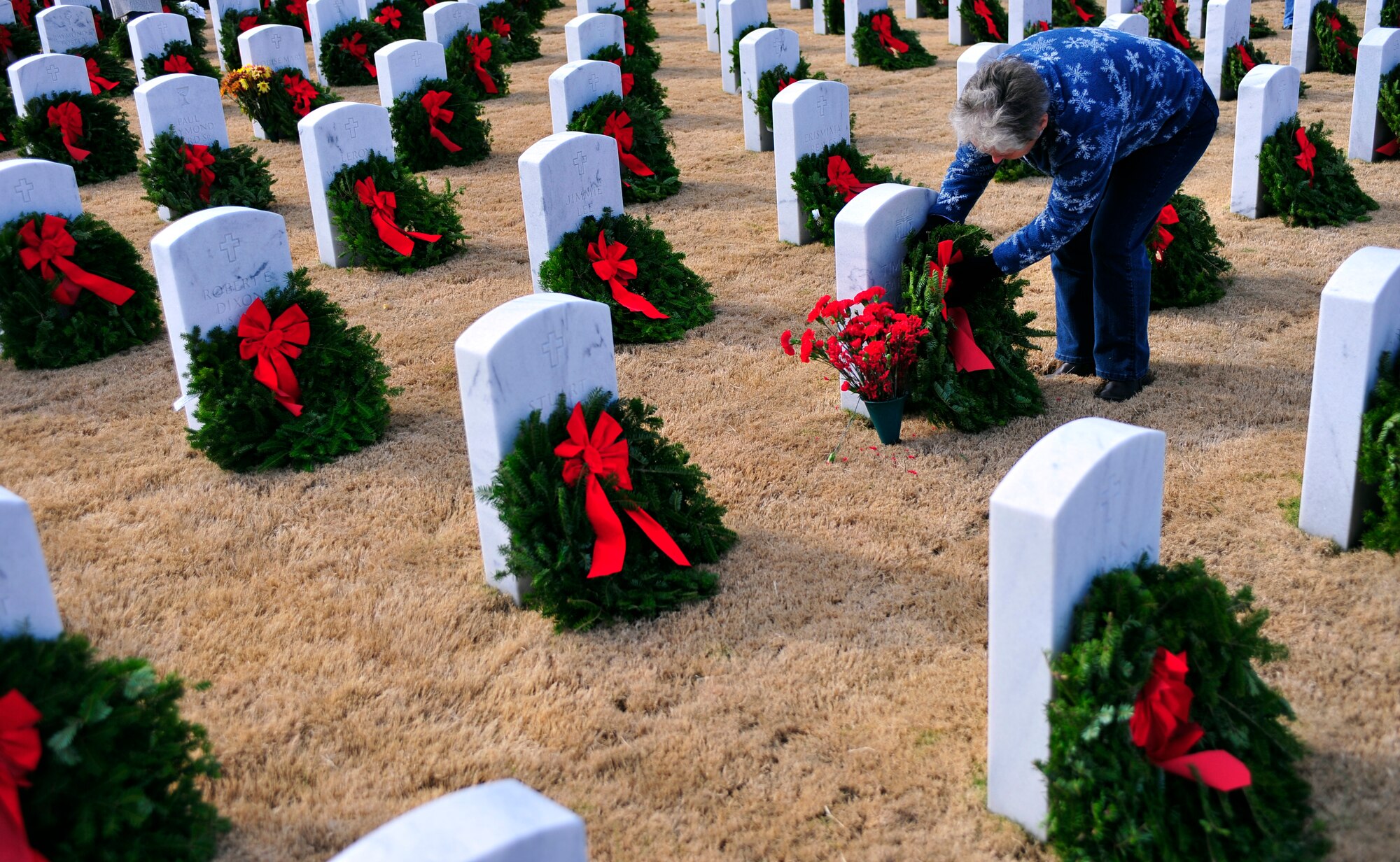 A volunteer adjusts a wreath on a gravestone at the Wreaths Across America ceremony at Fort Jackson National Cemetery, Columbia, S.C., Dec. 10, 2011. Wreaths Across America occurs the second Saturday of December every year. People gather to lay holiday wreaths on the gravestones at national military cemeteries. (U.S. Air Force photo/Senior Airman Daniel Phelps/Released)
