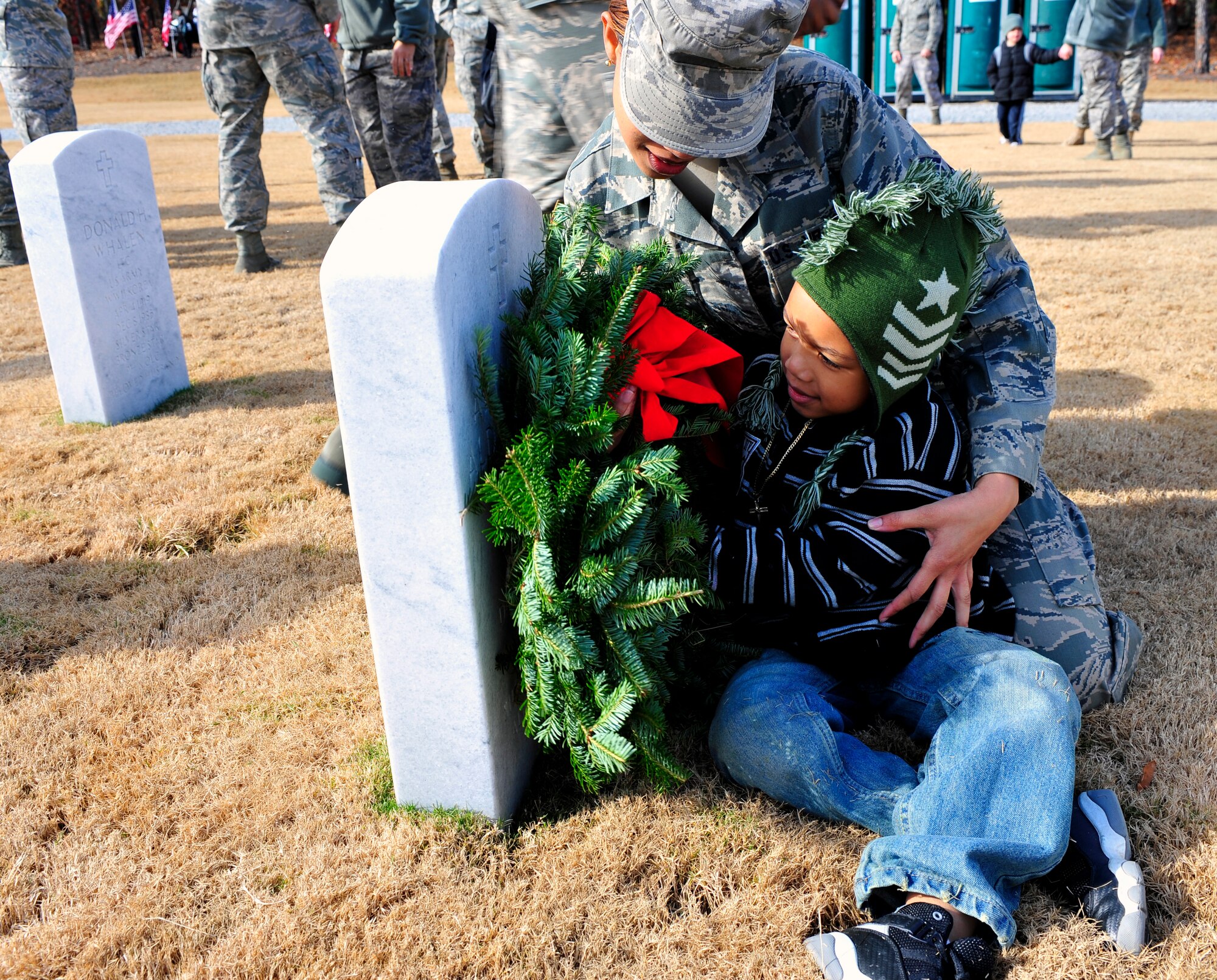 U.S. Air Force Staff Sgt. Chiquita Young, 20th Force Support Squadron, and her son Zion Tucker lay a wreath on a gravestone at the Wreaths Across America ceremony at Fort Jackson National Cemetery, Columbia, S.C., Dec. 10, 2011. Wreaths Across America occurs the second Saturday of December every year. People gather to lay holiday wreaths on the gravestones at national military cemeteries. (U.S. Air Force photo/Senior Airman Daniel Phelps/Released)