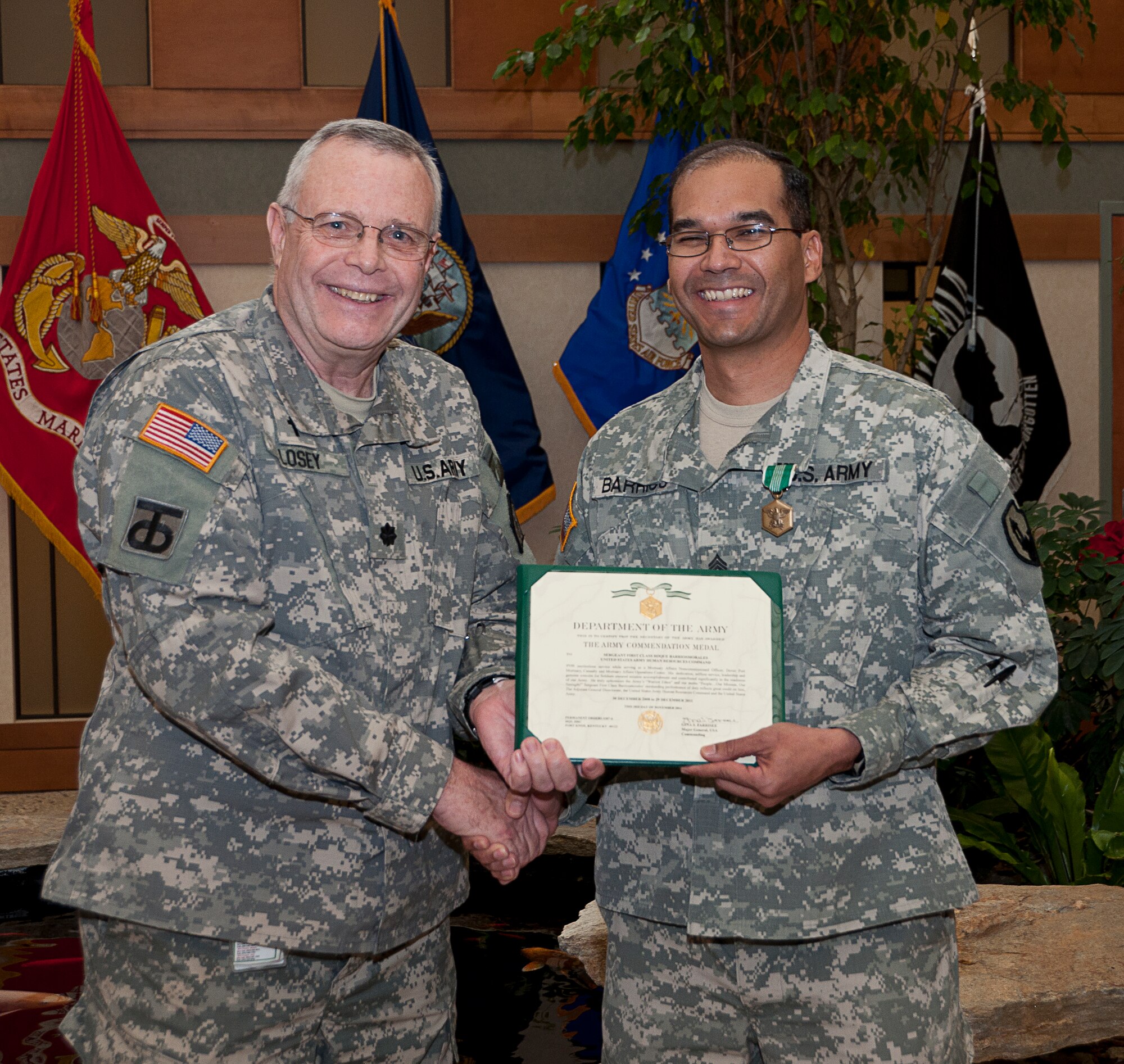 Chaplain (Lt. Col.) Gary W. Losey presents an Army Commendation medal to Sgt. First Class Rogue Barrios-Morales for service with the Army liaison team at the Charles C. Carson Center for Mortuary Affairs, Dover Air Force Base, Del., Dec. 9, 2011. Barrios-Morales is assigned to the 311th Quartermaster company/Mortuary Affairs at Aguadilla, Puerto Rico. (U.S. Air Force photo/Staff Sgt. Agustin Salazar)