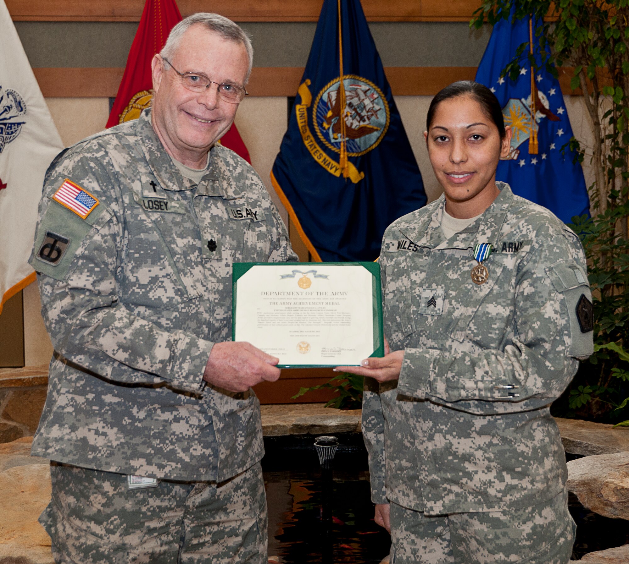 Chaplain (Lt. Col.) Gary W. Losey presents an Army Achievement medal to Sgt. Mariangelica Aviles for service with the Army liaison team at the Charles C. Carson Center for Mortuary Affairs, Dover Air Force Base, Del., Dec. 9, 2011. This is the  second Army Achievement medal for Aviles. (U.S. Air Force photo/Staff Sgt. Agustin Salazar)