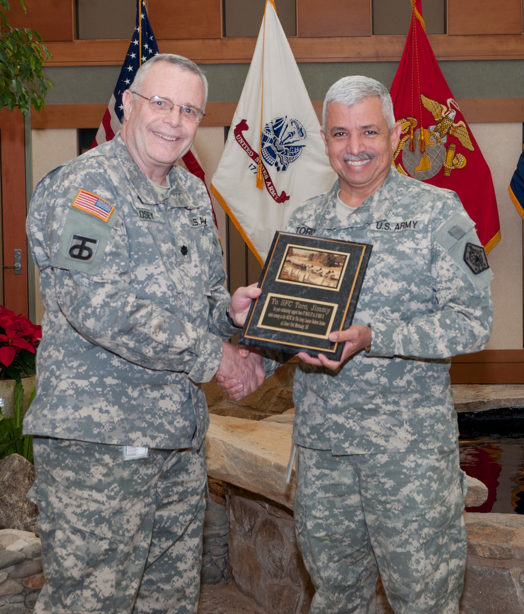Chaplin (Lt. Col.) Gary W. Losey presents a plaque to Sgt. First Class Jimmy Toro for meritorious service at the Charles C. Carson Center for Mortuary Affairs Operations, Dover Air Force Base, Del., Dec. 9, 2011. Toro has worked in the uniform section at the mortuary for the past five years. (U.S. Air Force photo/Staff Sgt. Salazar) 