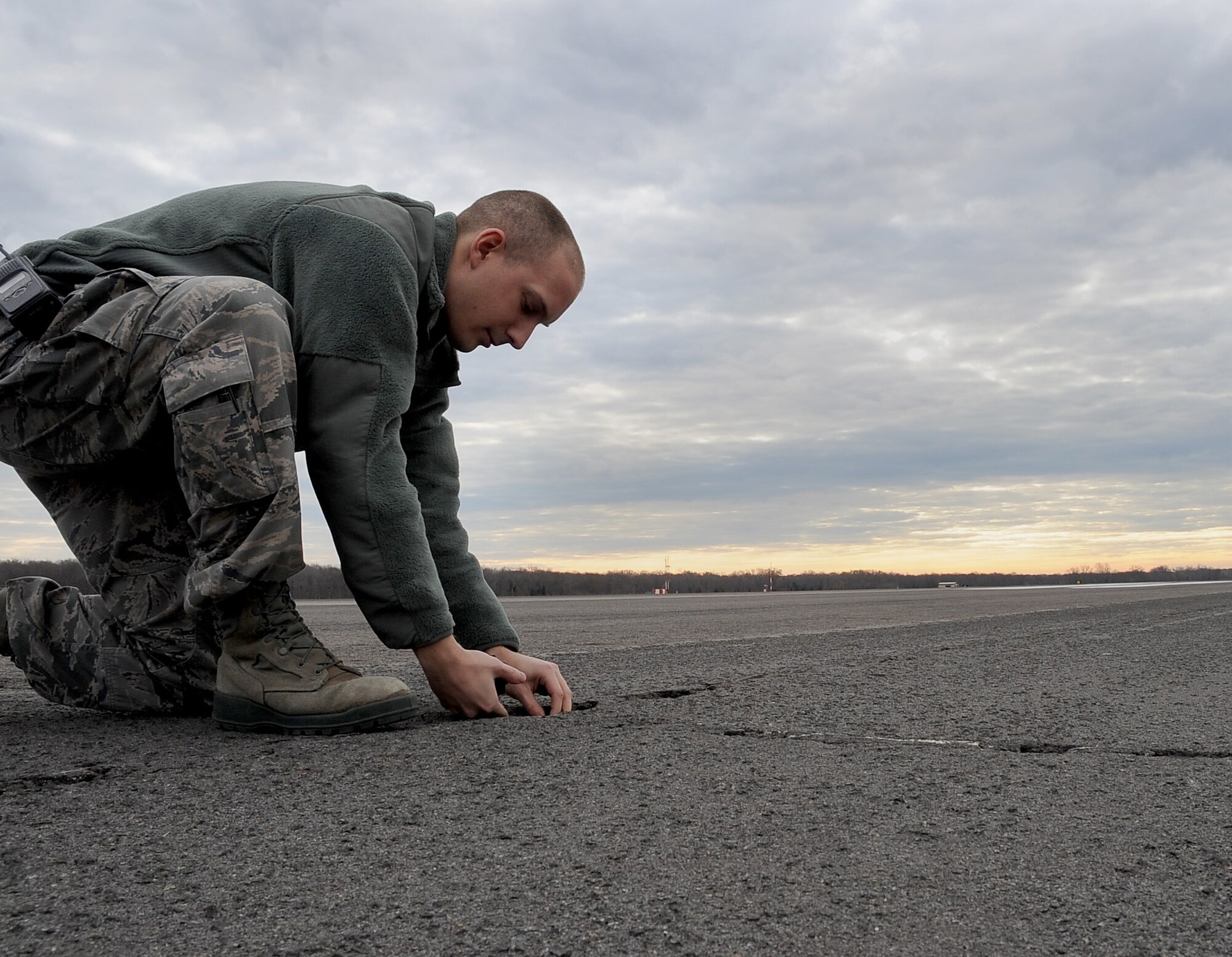 Airman 1st Class Mike Ross, 2nd Operations Support Squadron airfield management, picks up broken pavement Dec. 12 from the flightline on Barksdale Air Force Base, La. Barksdale Airmen perform sweeps on the airfield to pick up foreign object debris for flight operations to run smoothly. FOD usually consists of aircraft parts, rocks and broken pavement. (U.S. Air Force photo/Senior Airman Amber Ashcraft)(RELEASED)