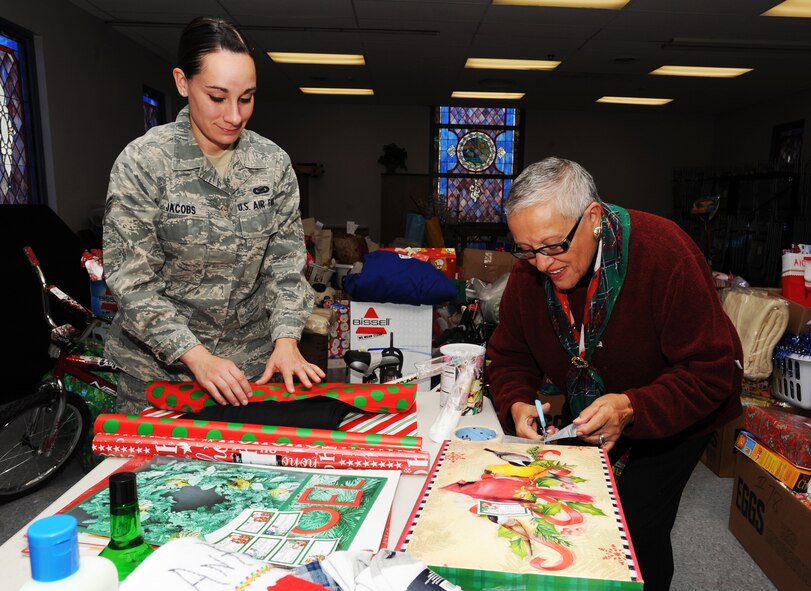 U.S. Air Force Senior Airman Amber Jacobs, 20th Fighter Wing, photographer, and Marisa Bailey, Operation True Giving volunteer, wrap and tape gifts at Palmetto Chapel, Shaw Air Force Base, S.C., Dec. 9, 2011. Operation True Giving is an annual program designed to help out families in the local Sumter community. The gifts and food are donated to nursing homes, singles and families. (U.S. Air Force photo by Airman 1st Class Tabatha Duarte/Released)
