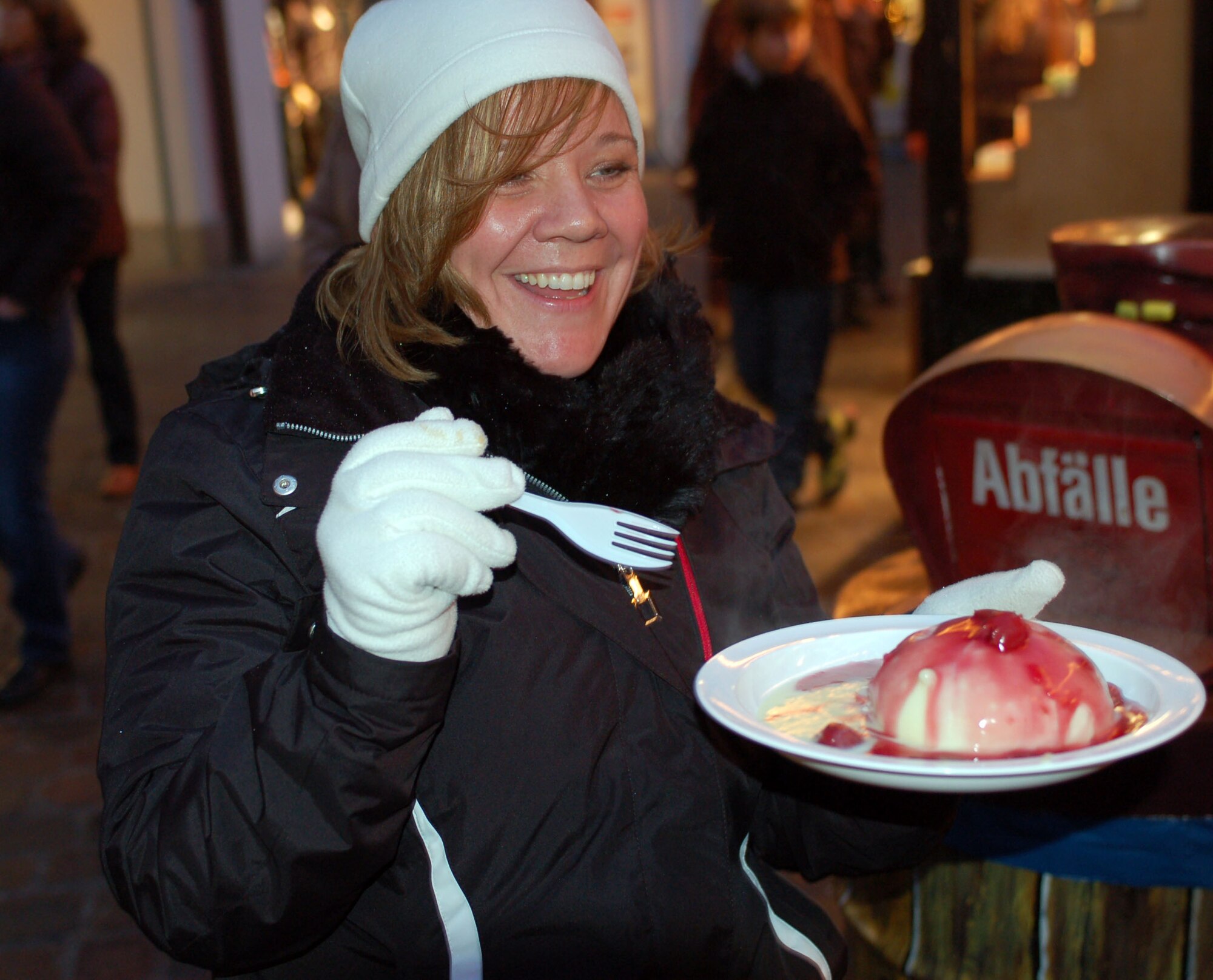 SPANGDAHLEM AIR BASE, Germany – A visitor enjoys a Dampfnudel, or steamed dumpling, at the Trier’s Weihnachtsmarkt Dec. 8 in the main market square in Trier. Steamed dumplings with warm cherries and vanilla sauce is a popular, traditional holiday food item in Germany. The Trier Weihnachtsmarkt is going on now through Dec. 22. Opening times are 10:30 a.m. - 8:30 p.m. Monday through Wednesday, 10:30 a.m. - 9:30 p.m. Thursday through Saturday, and 11 a.m. - 8:30 p.m. Sunday. Highlights include a performance by the U.S. Air Forces in Europe Brass Band from 6 - 7 p.m. Dec. 13. Music and entertainment is scheduled throughout each weekend, and Sankt Nikolaus will visit often. (U.S. Air Force photo/Iris Reiff)
