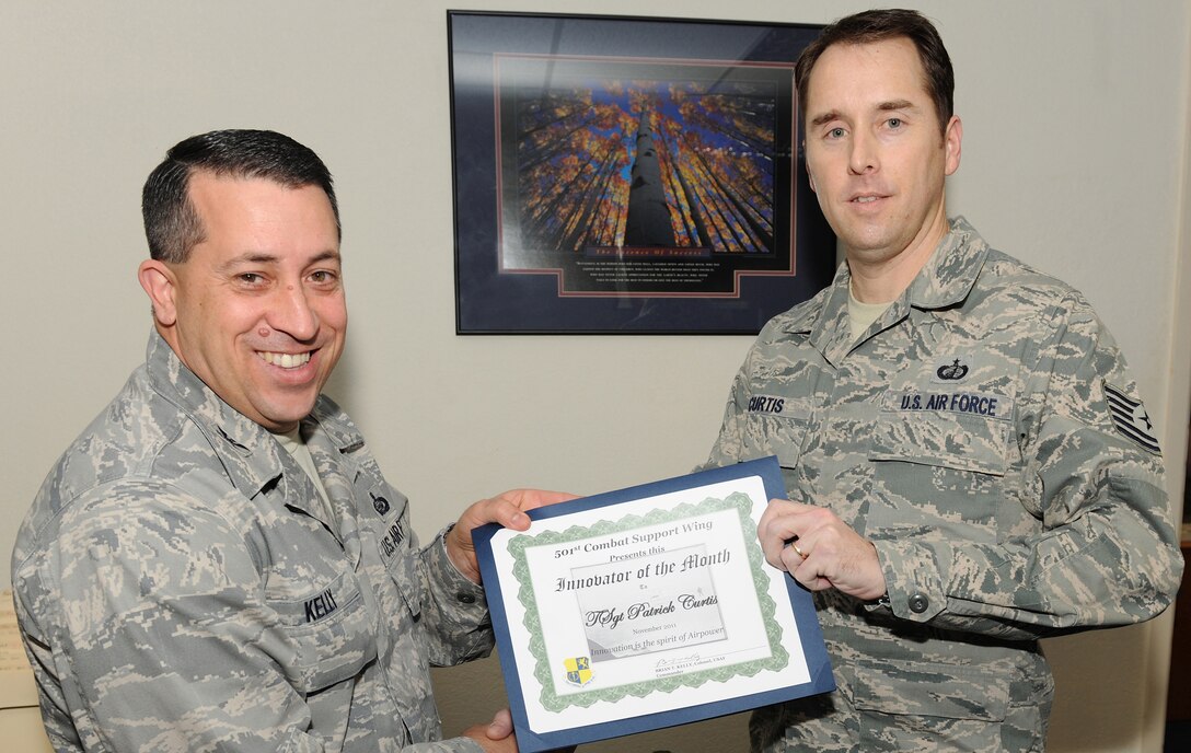 RAF ALCONBURY, United Kingdom - Col. Brian Kelly, 501st Combat Support Wing commander, presents the Innovator of the Month Award to Tech. Sgt. Patrick Curtis, 501st Combat Support Wing Finance Office. Curtis changed the process to fill out the civilian time sheet by making the process easier to use. (U.S. Air Force photo by Senior Airman Joel Mease) 