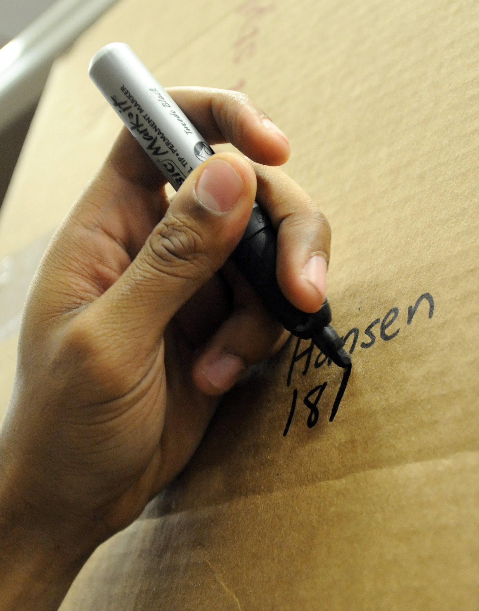 RAF MILDENHALL, England -- Senior Airman Keith Passmore, 100th Communications Squadron postal worker, writes the shelf location on the side of an inbound parcel at the post office here Dec. 9, 2011. This information allows parcel-pick-up-window attendants to easily locate packages when customers come to pick them up. (U.S. Air Force photo by Staff Sgt. Tabitha M. Lee)