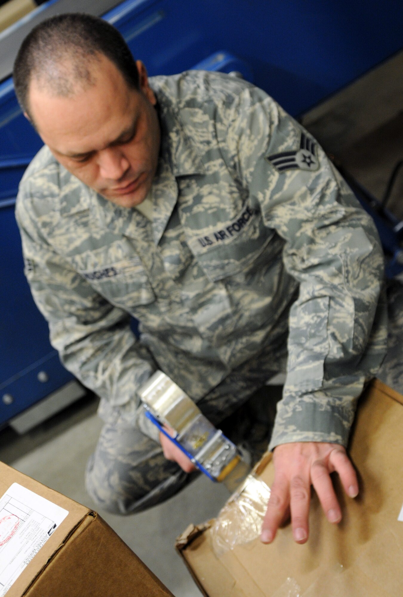 RAF MILDENHALL, England -- Senior Airman Michael Hughes, 100th Communications Squadron postal worker, secures an opening in a box as it comes off of a delivery truck at the post office here Dec. 9, 2011. The postal workers ensure boxes are secure before distributing them to customers. (U.S. Air Force photo by Staff Sgt. Tabitha M. Lee)