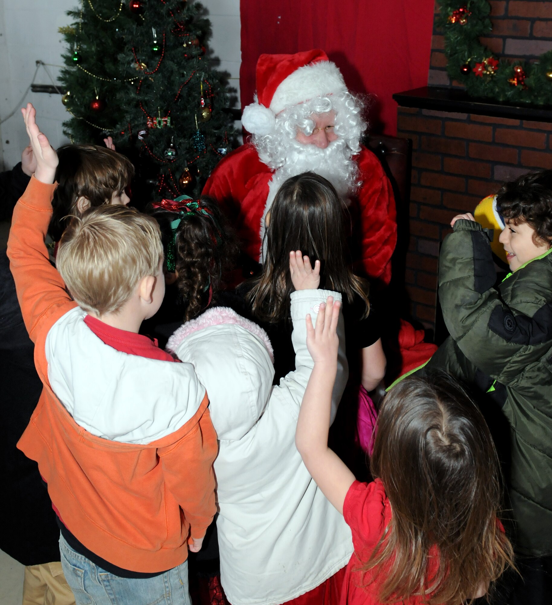 RAF MILDENHALL, England -- Children raise their hands indicating they have been good this year before lining up to sit on Santa Claus’ knee at Hanger 803 here Dec. 10, 2011. Santa, his elves and Rudolph arrived in a KC-135 Statotanker to visit with children from RAF Mildenhall during a children’s holiday party. (U.S. Air Force photo/Staff Sgt. Tabitha M. Lee)
