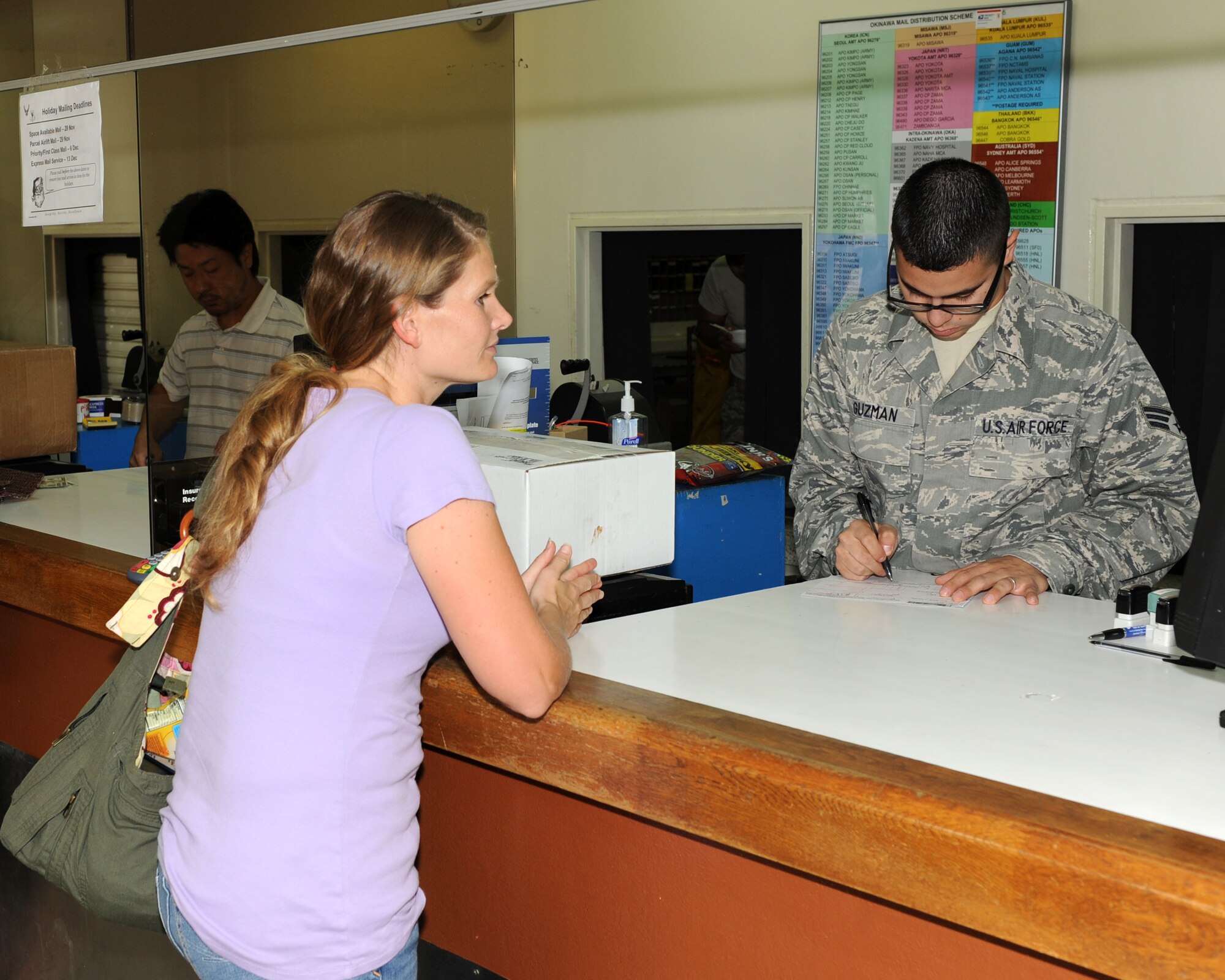 U.S. Air Force Senior Airman Adrian Guzman, 18th Communications Squadron postal clerk, helps Jennifer Obriant, a U.S. Air Force dependant, send a package during a trip to the post office on Kadena Air Base, Japan, Nov. 22, 2011. The post office recommends sending packages well in advance during the holiday season due to the high volume of mail processed. (U.S. Air Force photo by Junko Kinjo/Released)  