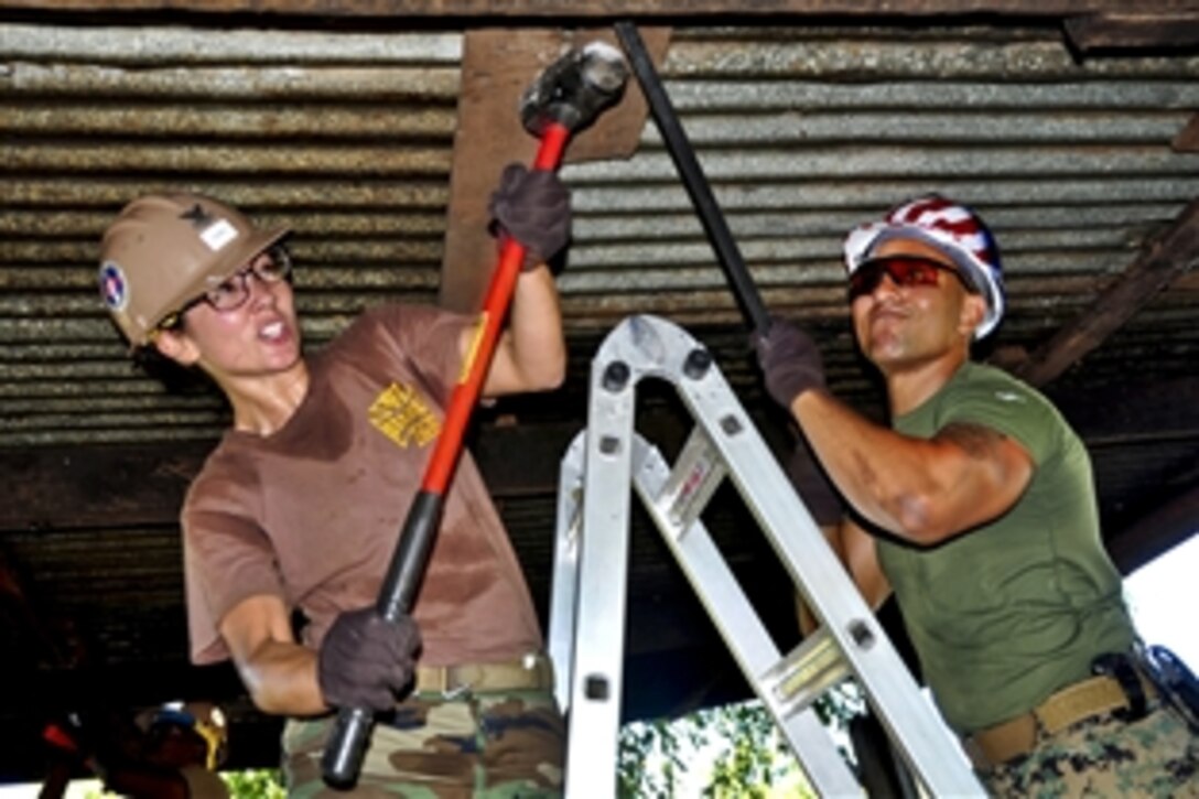 U.S. Navy Petty Officer 2nd Class Rejuny Caswell, left, and Marine Corps Staff Sgt. Mario Vargas try to remove a beam from a kitchen roof at Central Elementary School in La Union, El Salvador, Dec. 5, 2011, as part of a three-week repair project for High Speed Vessel-Southern Partnership Station 2012. Caswell is a steelworker assigned to Naval Mobile Construction Battalion 23.