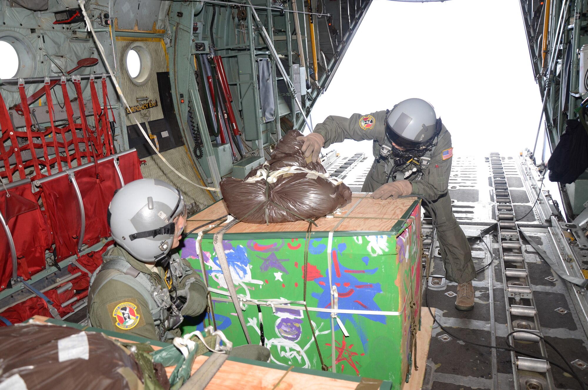 Over Fais Island, Micronesia -  Staff Sgt. Kyle Favorite and Master Sgt. Thomas Larson, 374th Airlift Wing loadmasters, prepare to push a pallet of medical supplies to the island Fais to treat an outbreak of dengue fever.  The island of Fais is located within the Yap state of the Micronesian Islands, and is one of the more than 50 islands that will receive care packages this holiday season as part of Operation Christmas Drop.  (U.S. Air Force photo/Senior Airman Veronica McMahon)