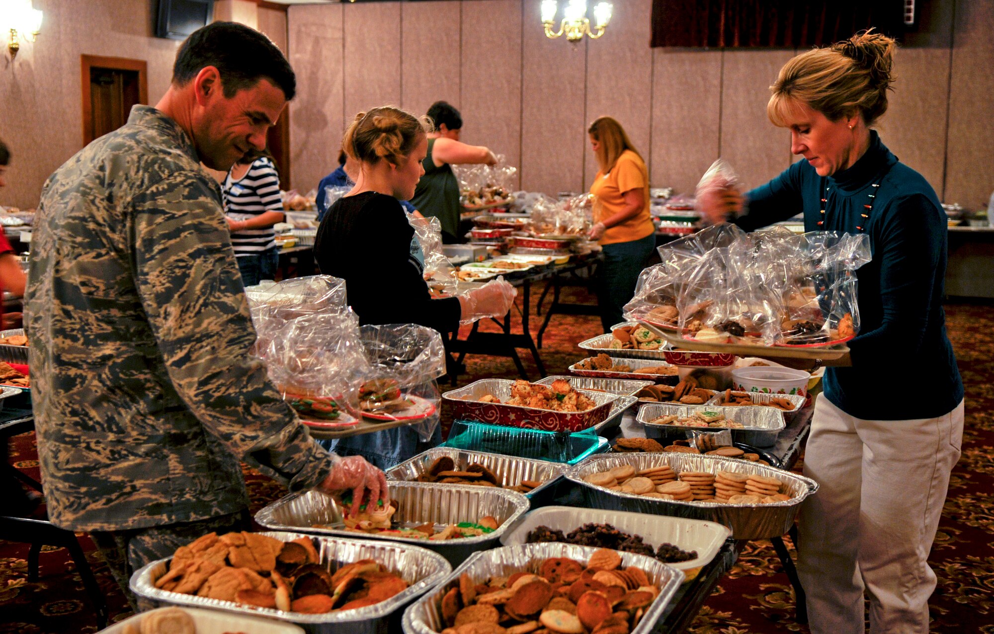 Brig. Gen. Matthew Molloy, 18th Wing commander, wife Kati and daughter Sarah, volunteer to package cookies made by Team Kadena to be delivered to single military members spending the holidays away from their families on Kadena Air Base, Japan, Dec. 13, 2011. This year's cookie drive surpassed 2010 by over 30,000 cookies, which was the intended goal at the start of this year's Kadena Cookie Caper. (U.S. Air Force photo by Airman 1st Class Tara A. Williamson/Released)