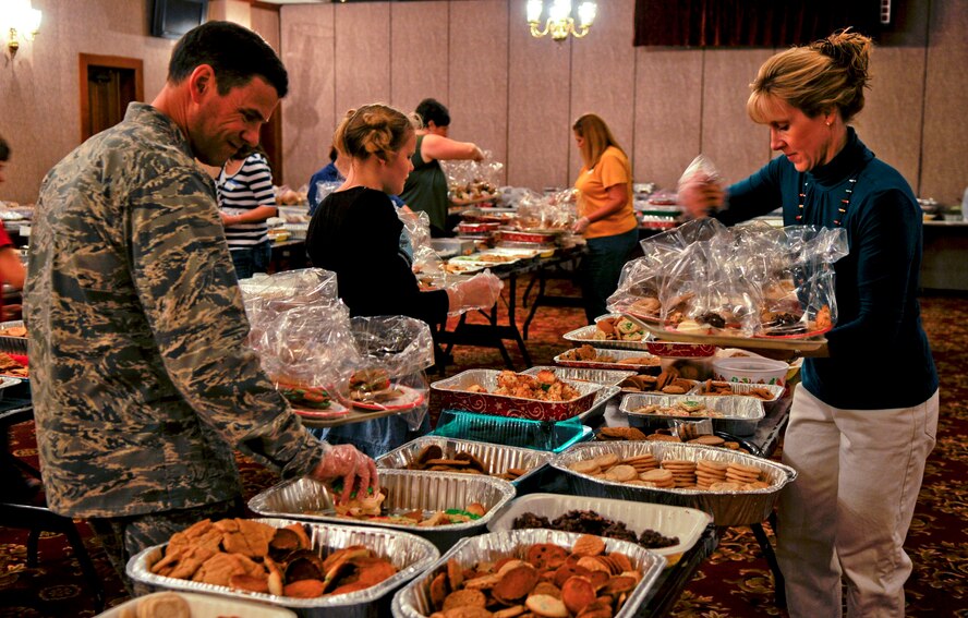 Brig. Gen. Matthew Molloy, 18th Wing commander, wife Kati and daughter Sarah, volunteer to package cookies made by Team Kadena to be delivered to single military members spending the holidays away from their families on Kadena Air Base, Japan, Dec. 13, 2011. This year's cookie drive surpassed 2010 by over 30,000 cookies, which was the intended goal at the start of this year's Kadena Cookie Caper. (U.S. Air Force photo by Airman 1st Class Tara A. Williamson/Released)