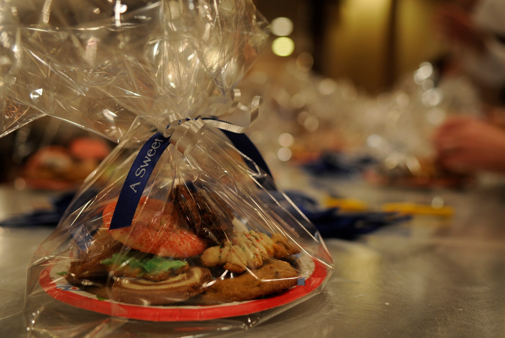 Cookies baked, packaged and wrapped with the love and support of Team Kadena are prepared by volunteers for the single military members in the dorms spending the holidays away from their families on Kadena Air Base, Japan, Dec. 13, 2011. Over 50 volunteers, both civilian and military, took time to package and tie each dozen cookies to be given to those in the dorms. (U.S. Air Force photo by Airman 1st Class Tara A. Williamson/Released)