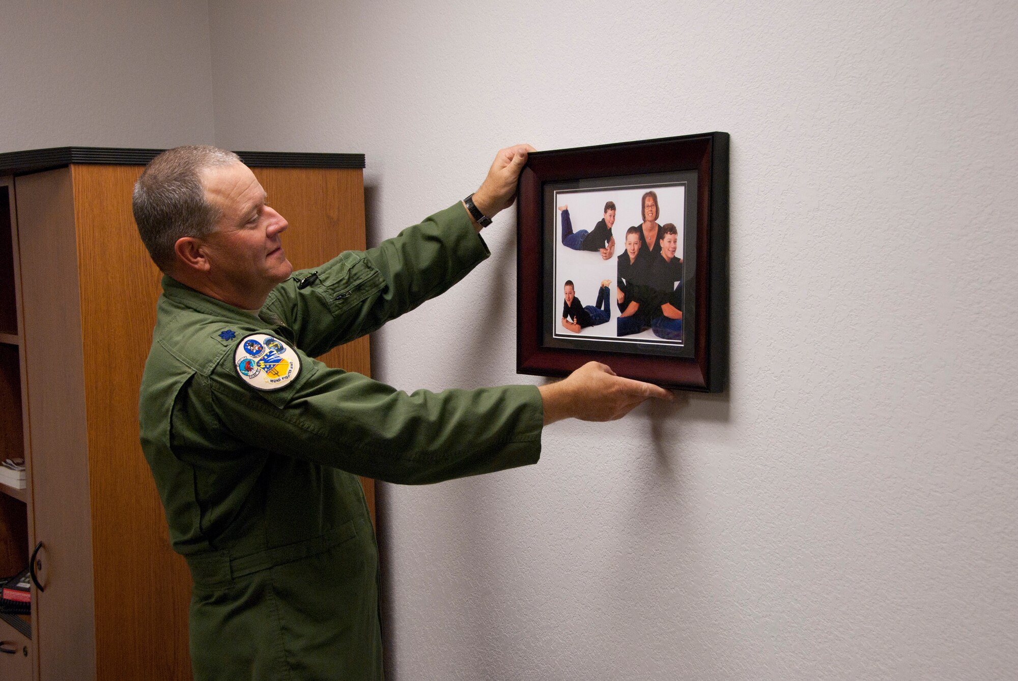 Lt. Col. Ken Rosson, 162nd Operations Group deputy commander, hangs family photos on the wall of his new office in building 44 on base at the 162nd Fighter Wing. The newly-renovated building will once again be home to the majority of the wing's pilot training mission. (U.S. Air Force photo/Master Sgt. Dave Neve)
