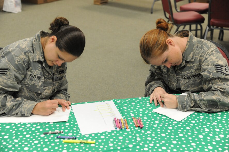 U.S. Air Force Senior Airman Autumn Sutter, 23rd Equipment Maintenance Squadron aerospace ground equipment journeyman, and Staff Sgt. Lindsay Shaw, 23rd EMS aircraft metals technology technician, decorate cookie bags at Moody Air Force Base, Ga., Dec. 13, 2011. Shaw and Sutter designed and decorated the cookie bags with various Christmas themes. Each bag contains a dozen cookies, a small bag of candy, cashews and a bag of popcorn. (U.S. Air Force photo by Airman 1st Class Paul Francis/Released)
