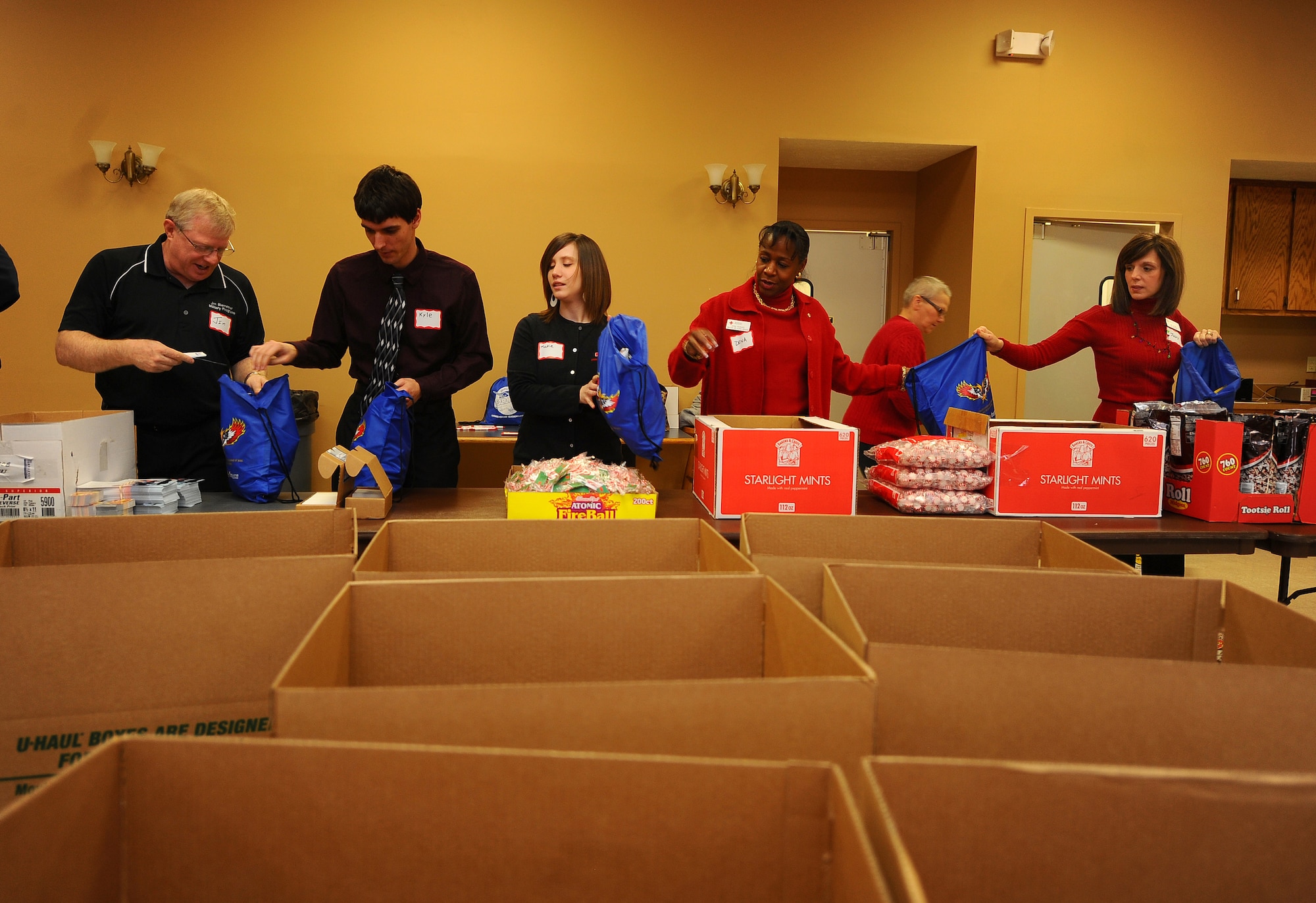 Bags being filled to capacity with treats get handed down the assembly line of volunteers from the Bellevue area before being transferred to large cardboard boxes in Bellevue, Neb., Dec. 13.  The gift bags are designed to add a little holiday cheer to Airman that are unable to go home over the holiday season.  More than 650 bags were put to together.  (U.S. Air Force Photo by Josh Plueger/Released)