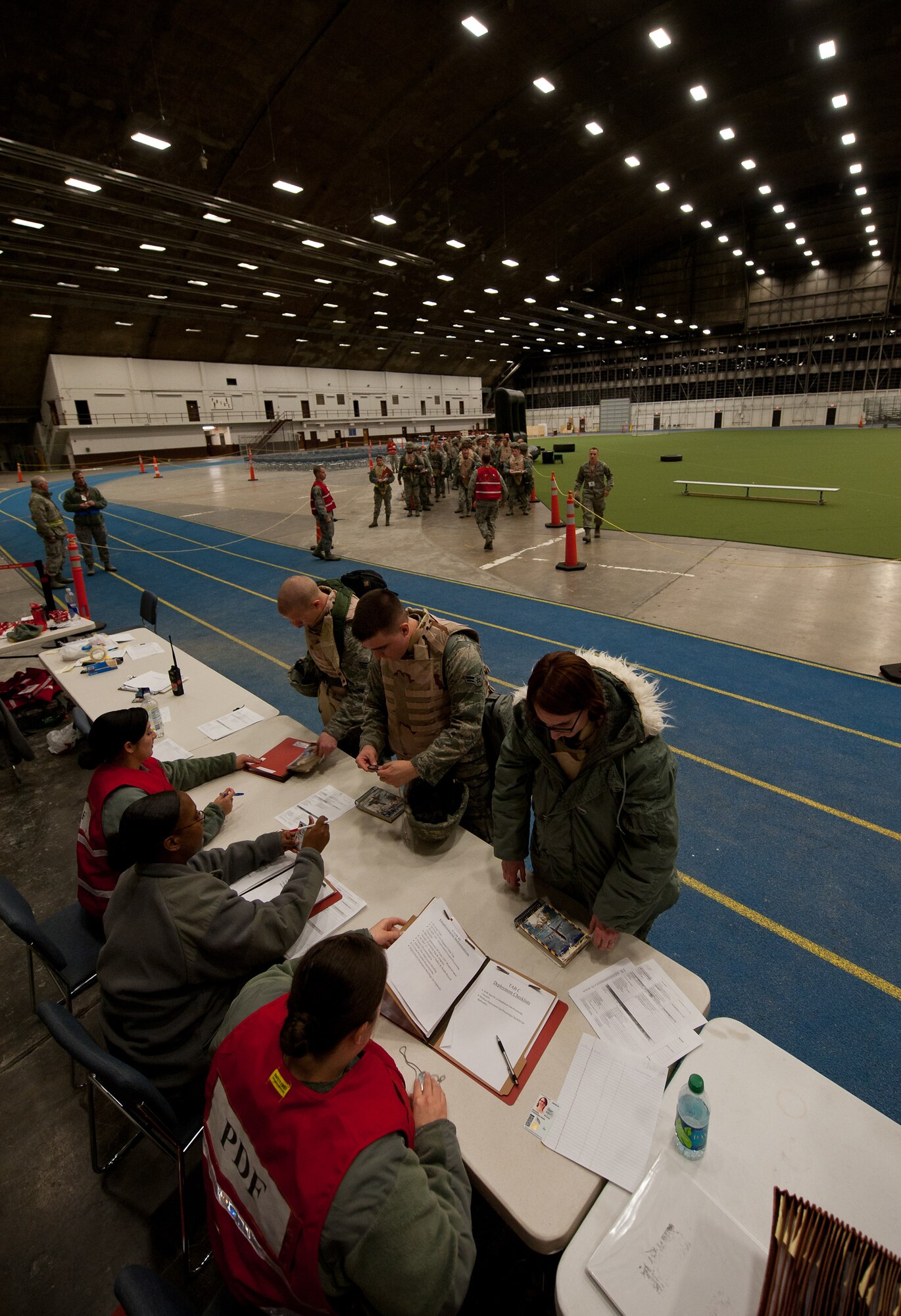 Airmen of the 28th Bomb Wing approach a Personnel Deployment Function line in the Pride Hangar to quickly outprocess the base for a simulated mass deployment during an Operational Readiness Exercise on Ellsworth Air Force Base, S.D., Dec. 7, 2011. The PDF staff checked deployment folders for accurate information to ensure a smooth and timely process of deployers. (U.S. Air Force photo by Airman 1st Class Kate Thornton/Released)