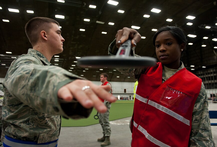 Airman 1st Class Precilla Lawrence, 28th Bomb Wing Judge Advocate paralegal, scans Airman 1st Class Christopher Andrews, 28th Civil Engineer Squadron power production apprentice, with a metal detector in the Pride Hangar during an Operational Readiness Exercise on Ellsworth Air Force Base, S.D., Dec. 7, 2011. Airmen working the Transportation Security Administration detail checked bags for prohibited items and safety hazards. (U.S. Air Force photo by Airman 1st Class Kate Thornton/Released)