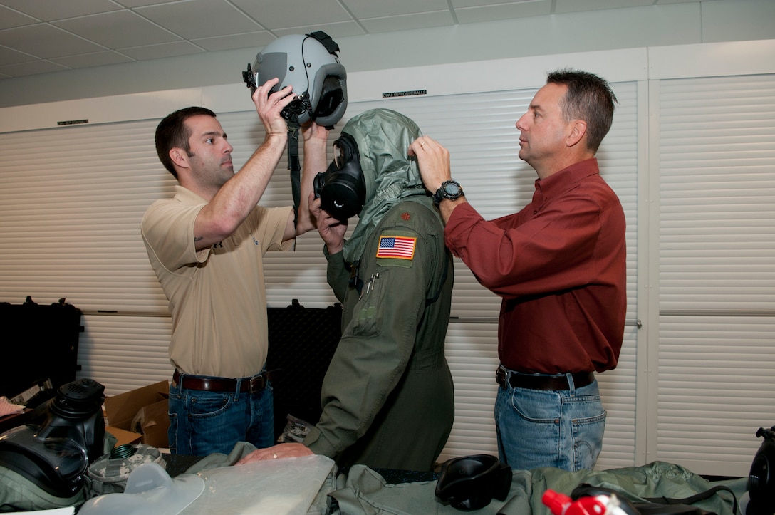 Steve Leadore and Kevin O'Neal, Joint Service Aircrew-Fixed Wing (JSAM-FW) research team members, assist Major Jeff Musser, a pilot for the 167th Airlift Squadron,  don equipment during an assessment of the equipment at the 167th Airlift Wing. A Department of Defense research team working on the development of a joint service aircrew mask conducted field assessments at the West Virginia Air National Guard unit in Martinsburg, WV,  December 7, 2011. The team had aircrew in each of the flying positions don the mask and accompanying gear and perform their duties on a C-5 aircraft. (Air National Guard photo by Master Sgt. Emily Beightol-Deyerle)