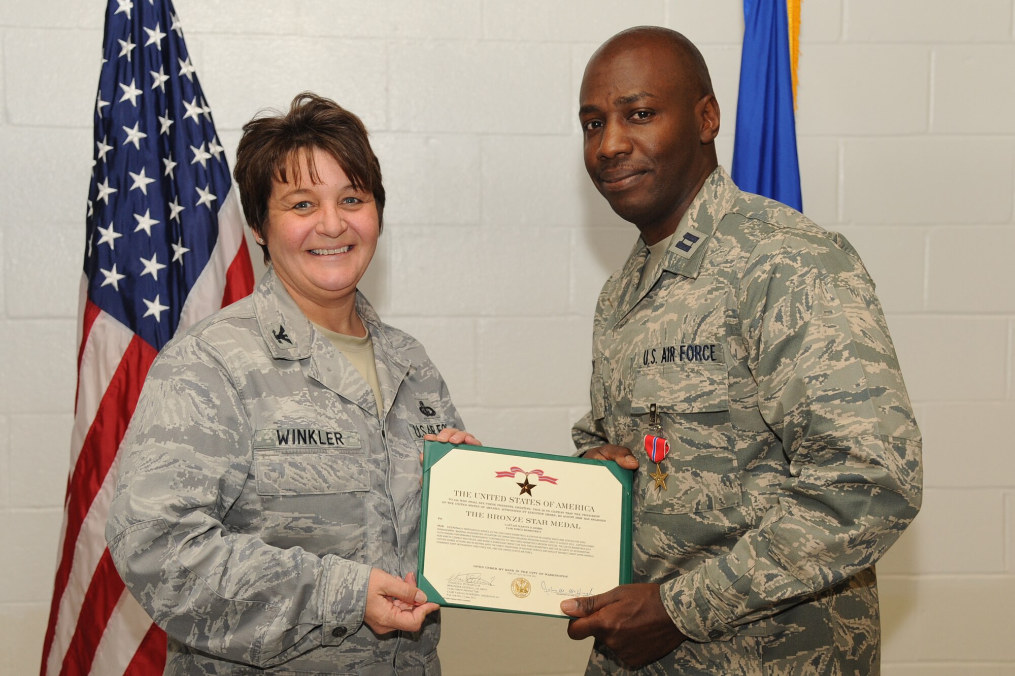 Col. Ann Winkler, 4th Mission Support Group commander, presents Capt. Marvin Dobbs, 4th Communications Squadron director of operations, with the Bronze Star medal on Seymour Johnson Air Force Base, N.C., Dec. 13, 2011. Dobbs was awarded the medal by establishing the Afghan Automated Biometric Identification file system, which distributed more than 1,500 records a week in accordance with the United States and the Government of the Islamic Republic of Afghanistan sharing agreement. Winkler is a native of Kansas City, Mo. and Dobbs is a native of Aikens, S.C. (U.S. Air Force photo by Senior Airman Whitney Stanfield) 