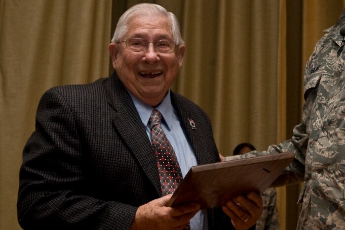 U.S. Air Force Col. Steven Garland, 99th Air Base Wing commander, named retired Chief Master Sgt. Henry S. Fouts, the 99 ABW honorary command chief during a commander's call Dec. 9, 2011, at Nellis Air Force Base, Nev. In Fouts' honor, the Diamondback Award was created to emphasize the accomplishments of Airmen who help keep Fouts' spirit of innovation alive. (U.S. Air Force photo by Airman 1st Class Daniel Hughes/Released)