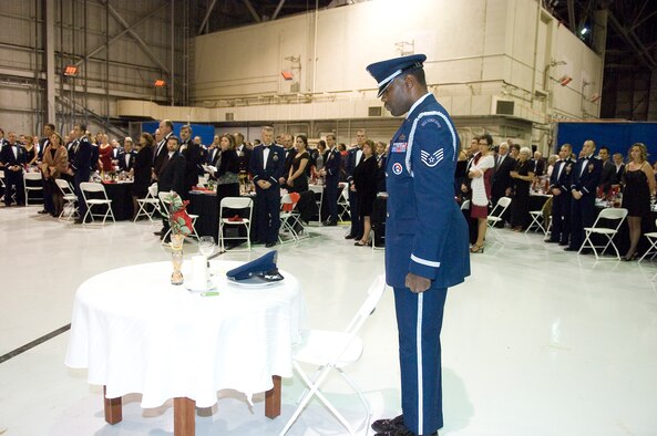 Staff Sgt. Leopold Douglas, a member of the Blue Eagle Honor Guard, recognizes an empty seat and place setting, always left vacant to remember POWs and MIAs, during the USAF Test Pilot School graduation in Hangar 1414, Dec. 10. Twenty-three students graduated from Class 11A. (U.S. Air Force photo by Rob Densmore)
