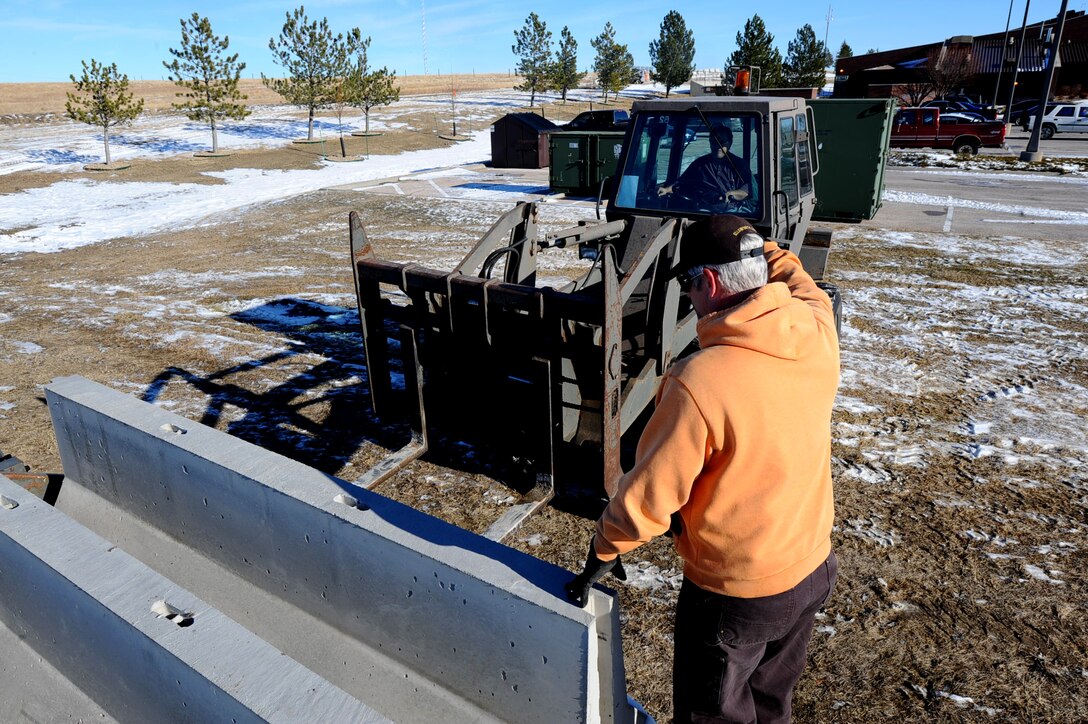Kevin Holman directs Elias Davila, both civilian contractors with the 28th Civil Engineer Squadron, while they unload concrete barriers during the Operational Readiness Exercise on Ellsworth Air Force Base, S.D., Dec. 6, 2011. The ORE challenges the ability of Airmen to operate effectively in a wartime environment. (U.S. Air Force photo by Airman 1st Class Zachary Hada/Released)