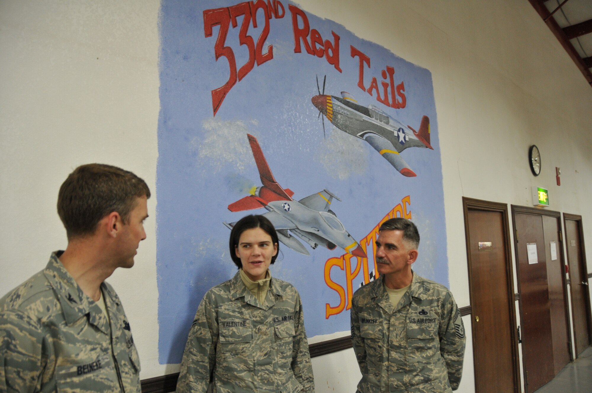 Col. Paul Beineke, 332nd Air Expeditionary Wing commander, and Chief Master Sgt. John Brinkley, 332nd AEW command chief, talk with Airman 1st Class Laura Valentine about the “Red Tails” mural she spent over 42 hours creating at an undisclosed location in Southwest Asia Dec. 12, 2011. Valentine, 332nd Expeditionary Operations Support Squadron weather forecaster/observer, is deployed from Shaw Air Force Base, S.C., and used her time off to paint the mural on an interior wall of the 332nd AEW dining facility. (U.S. Air Force photo by Master Sgt. Paul Mann)