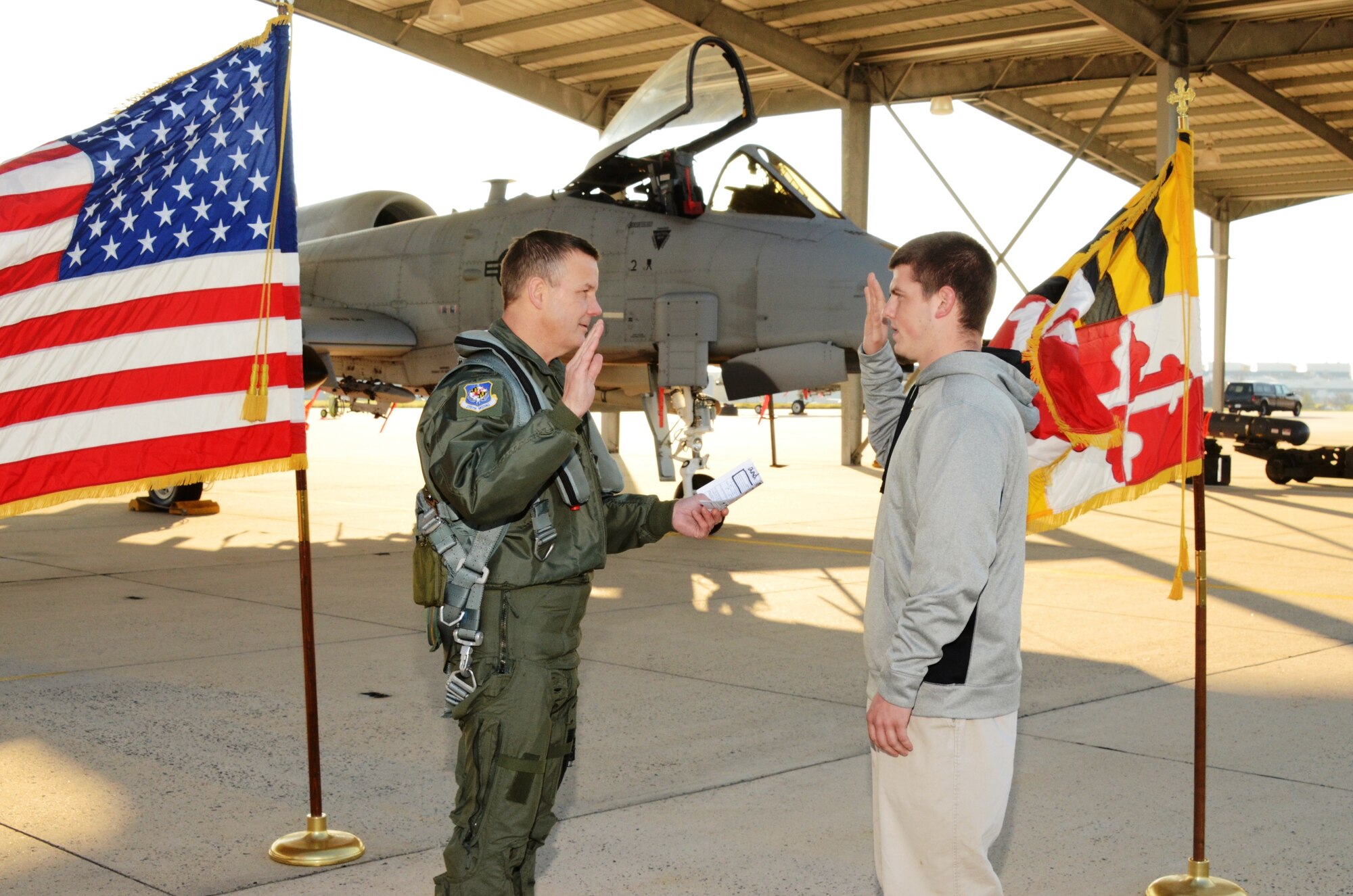 New enlistee John G. Weinhold repeats the enlistment oath from Col. Scott L. Kelly, commander of the 175th Wing Maryland Air National Guard, at Warfield Air National Guard Base, Baltimore, MD. 

Federal law requires everyone who enlists or re-enlists in the Armed Forces of the United States to take the enlistment oath. The oath of enlistment into the United States Armed Forces is administered by any commissioned officer to any person enlisting or re-enlisting for a term of service into any branch of the military. The officer asks the person, or persons, to raise their right hand and repeat the oath after him. The oath is traditionally performed in front of the United States Flag and other flags, such as the state flag, military branch flag, and unit guidon may be present. 

John enlisted into the Maryland Air Guard for six years as a A-10C Crew Chief.  

Col Kelly had referred John and his friend to the guard under the referral program.   Air National Guard Referral Rewards Program is a voluntary recruitment referral program where members who successfully help recruit a new member are rewarded with incentives.
 (U.S. Air Force photo by Master Sgt. Ed Bard/RELEASED)
