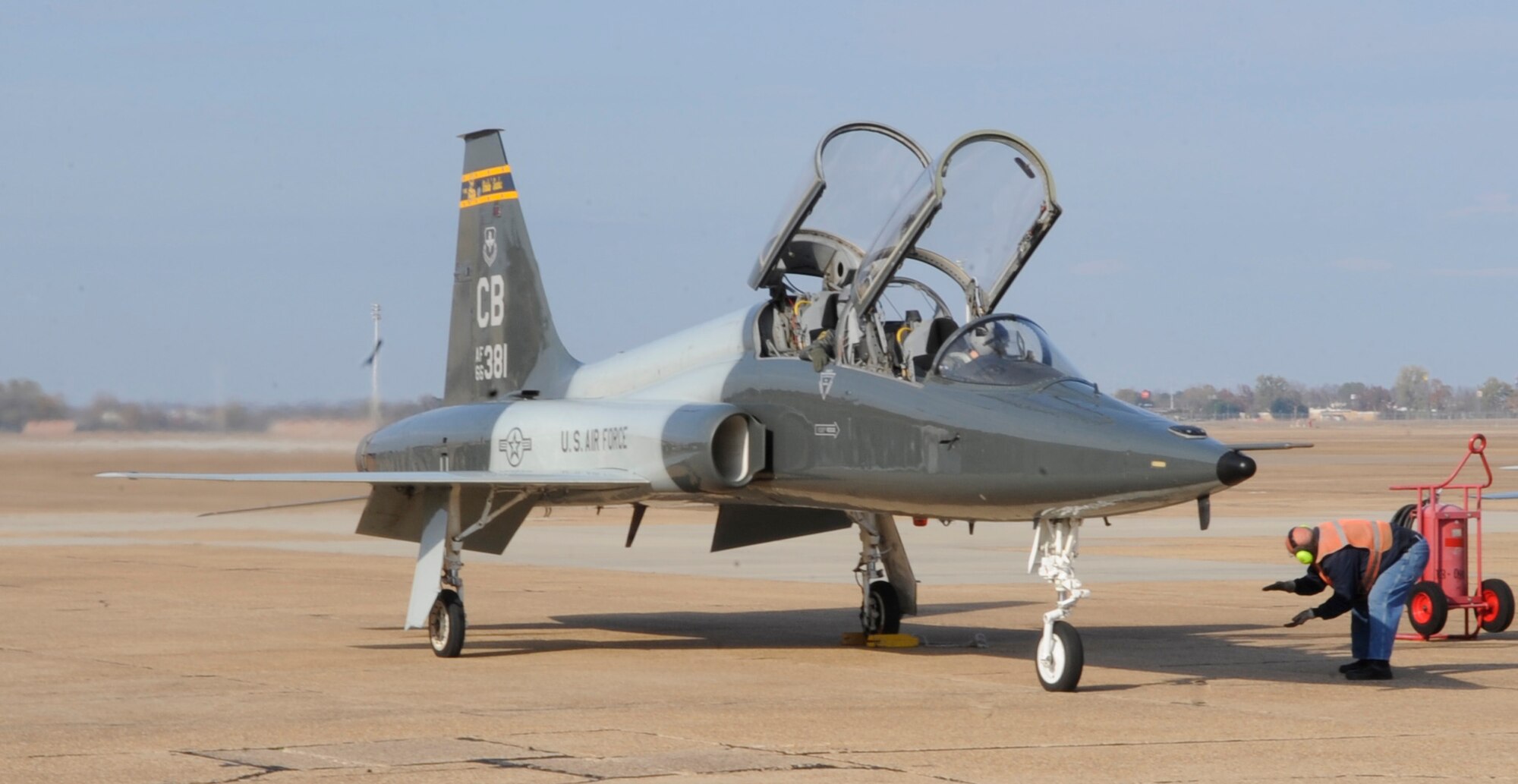 Maj. Robert Faustmann and 2nd Lt. Allie Johnston, 50th Flying Training Squadron from Columbus Air Force Base, Miss., use hand signals to communicate with a member of Transient Alert on Barksdale Air Force Base, La., Dec. 9. Barksdale hosts approximately 100 transient aircraft a month, ranging from training missions to aircraft refueling stops. (U.S. Air Force photo/2nd Lt. Tori Lalich)(RELEASED)