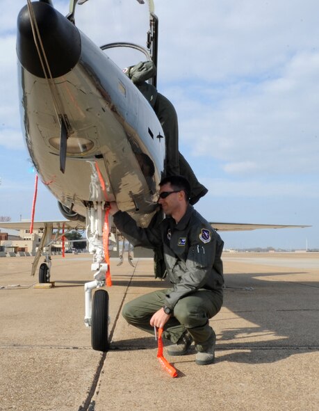 Instructor pilot Maj. Robert Faustmann, 50th Flying Training Squadron from Columbus Air Force Base, Miss., removes flags and pins from the nose of a T-38C Talon training jet on Barksdale Air Force Base, La., Dec. 9. Barksdale hosts approximately 100 transient aircraft a month, ranging training missions to aircraft refueling stops. (U.S. Air Force photo/2nd Lt. Tori Lalich)(RELEASED)
