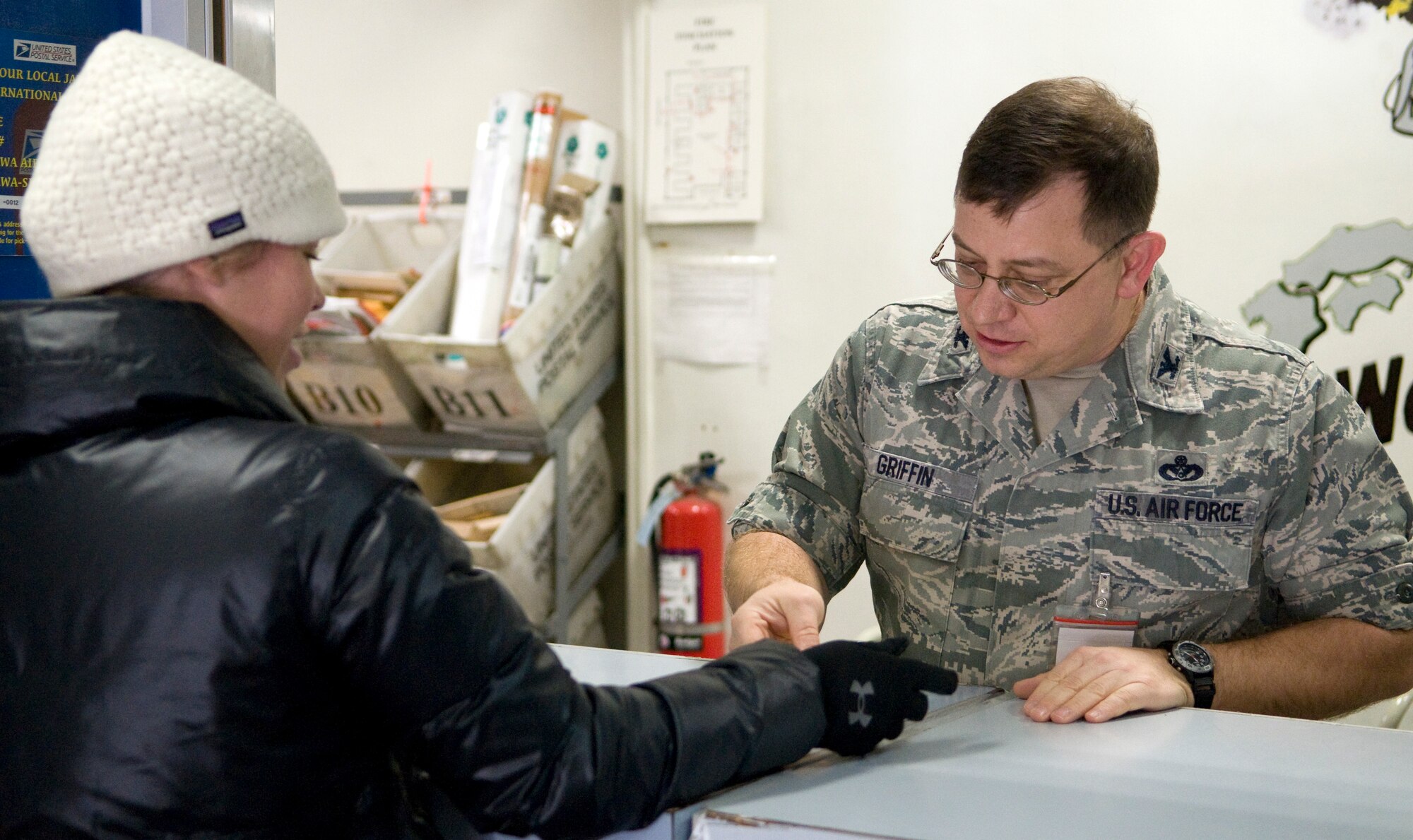 MISAWA AIR BASE, Japan – Col. John Griffin, 35th Mission Support Group commander, checks Jocelyn O’Reilly’s identification before giving her a parcel at the base post office, here Dec. 13. During the holiday season, the post office receives an increase in mail flow and relies on volunteers to assist in meeting their duty requirements. The post office has extended its hours from 10 a.m. to 7 p.m., Monday through Saturday and noon to 3 p.m. on Sundays, until Dec. 23. The Exchange Annex will also be available from 10 a.m. to 2 p.m. on Mondays, Wednesdays and Fridays until Dec. 16. (U.S. Air Force photo by Airman 1st Class Kaleb J Snay)   