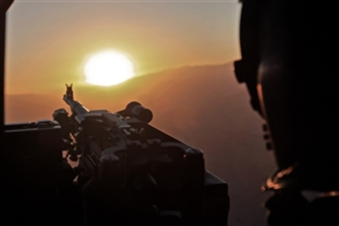 U.S. Army Spc. Kimberly Nicholls mans her M240 Bravo machine gun during sunset while flying over Logar province, Afghanistan, Dec. 8, 2011. Nicholls is a UH-60M Black Hawk helicopter crew chief assigned to Company B, 2-82 Task Force Corsair, 82nd Combat Aviation Brigade. Nicholls helps escort passengers from Forward Operating Base Salerno to Kabul International Airport.