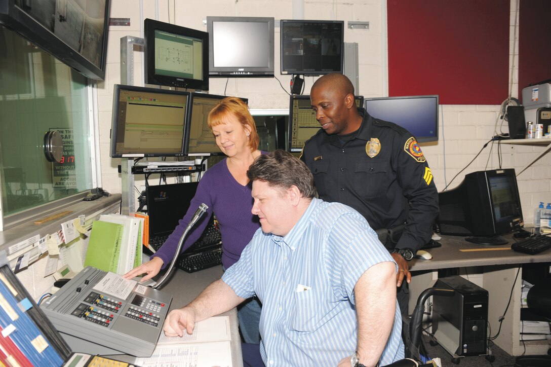 Robbin Lamb, spectrum and land mobile radio manager with Marine Corps Logistics Base Albany, demonstrates how to use the new radio dispatch console to Kevin Armstrong, sitting, emergency services   dispatcher, and Sgt. Charles Duncan, patrol sergeant/desk sergeant, Marine Corps Police Department, recently.