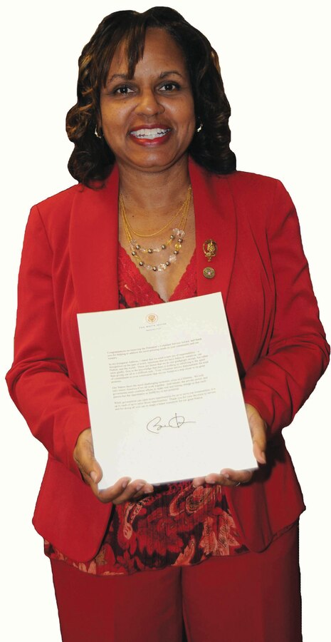 Karen Hartman, logistics management specialist, Marine Corps Systems Command, showcases a congratulatory letter from President Barack Obama for her volunteer service.