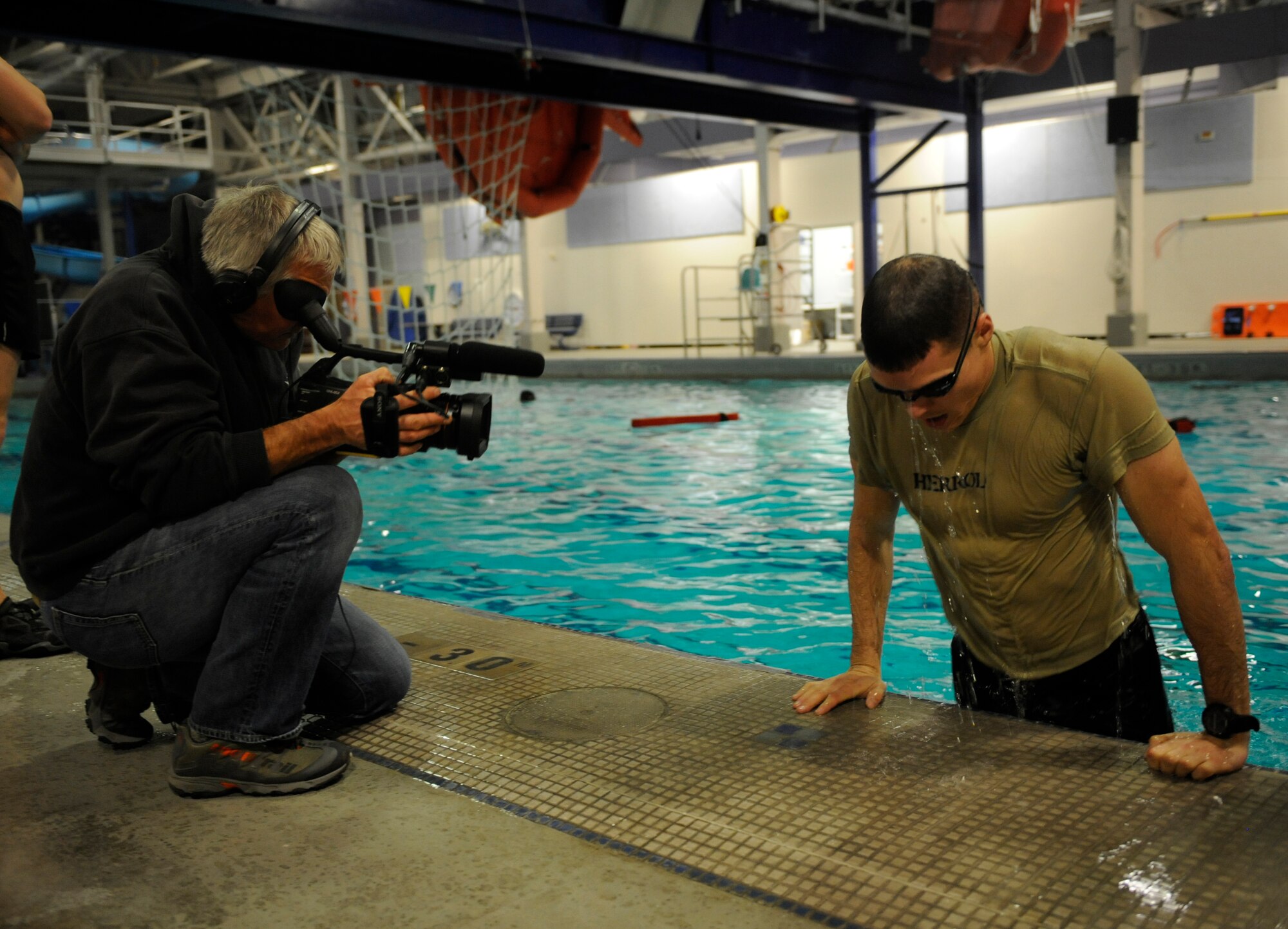Michael Graber, independent camera man, who is working with National Geographic to produce a story on Survival, Evasion, Resistance and Escape training, films Airman 1st Class Paul Herrol, SERE candidate, 22nd Training Squadron, as he performs an exercise at the aqua center Dec. 6. (U.S. Air Force photo/Airman 1st Class Earlandez Young) 