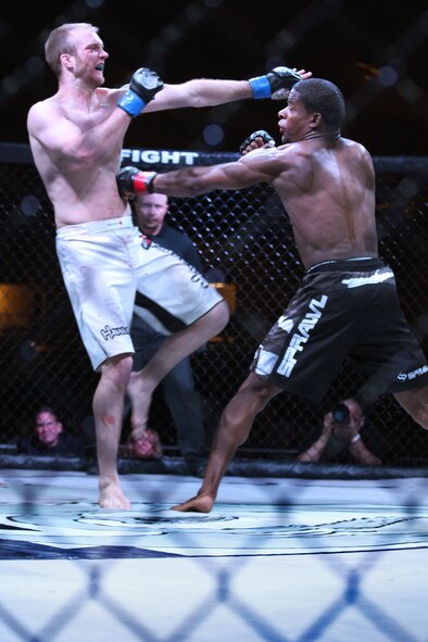 John Sparks, a kickboxer from Albuquerque, N.M., falls back as U.S. Air Force Staff. Sgt. Marc Hightower, 27th Special Operations Component Maintenance Squadron, hits him with a body shot during the second round in a Mixed Martial Arts competition in Clovis N.M., Dec. 10.  Hightower, competing a second time in MMA as an amateur fighter, won his match against Sparks after three rounds.  (U.S. Air Force photo by Senior Airman Jette Carr)
