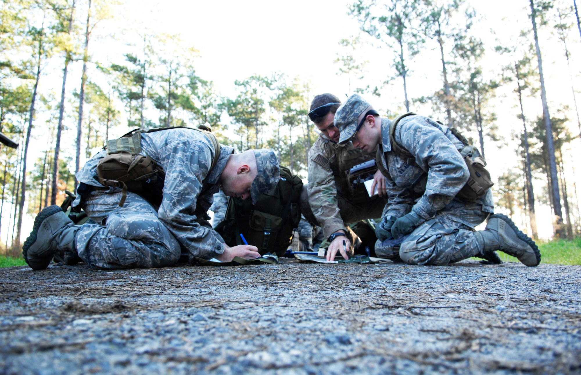 U.S. Air Force Academy Cadet Mike Temple, left, works to plot a course with Air Force ROTC Cadet Matthew Kinahan, right, as Tech. Sgt. John Moseley, 13th Air Support Operations Squadron tactical air control party member from Fort Carlson, Colo., gives pointers Dec. 13, 2011. The cadets were two of 32 men who came to Moody Air Force Base, Ga., in hopes of making in through the air liaison officer assessment course. (U.S. Air Force photo by Senior Airman Brigitte N. Brantley/Released)