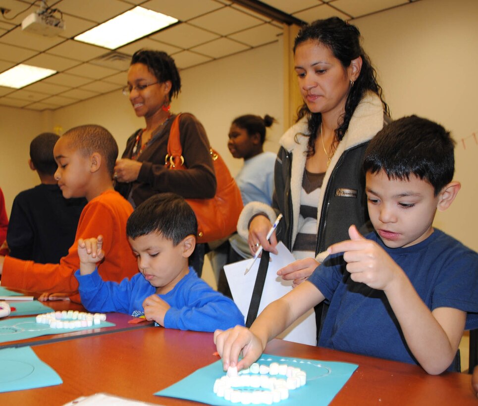 Pablo Rosa (left), 4, and his brother, Jesus Rosa, 6, make snow men with marshmallows as their mother, Lisandra Rosa, looks on. (Photo by Toni Guagenti)