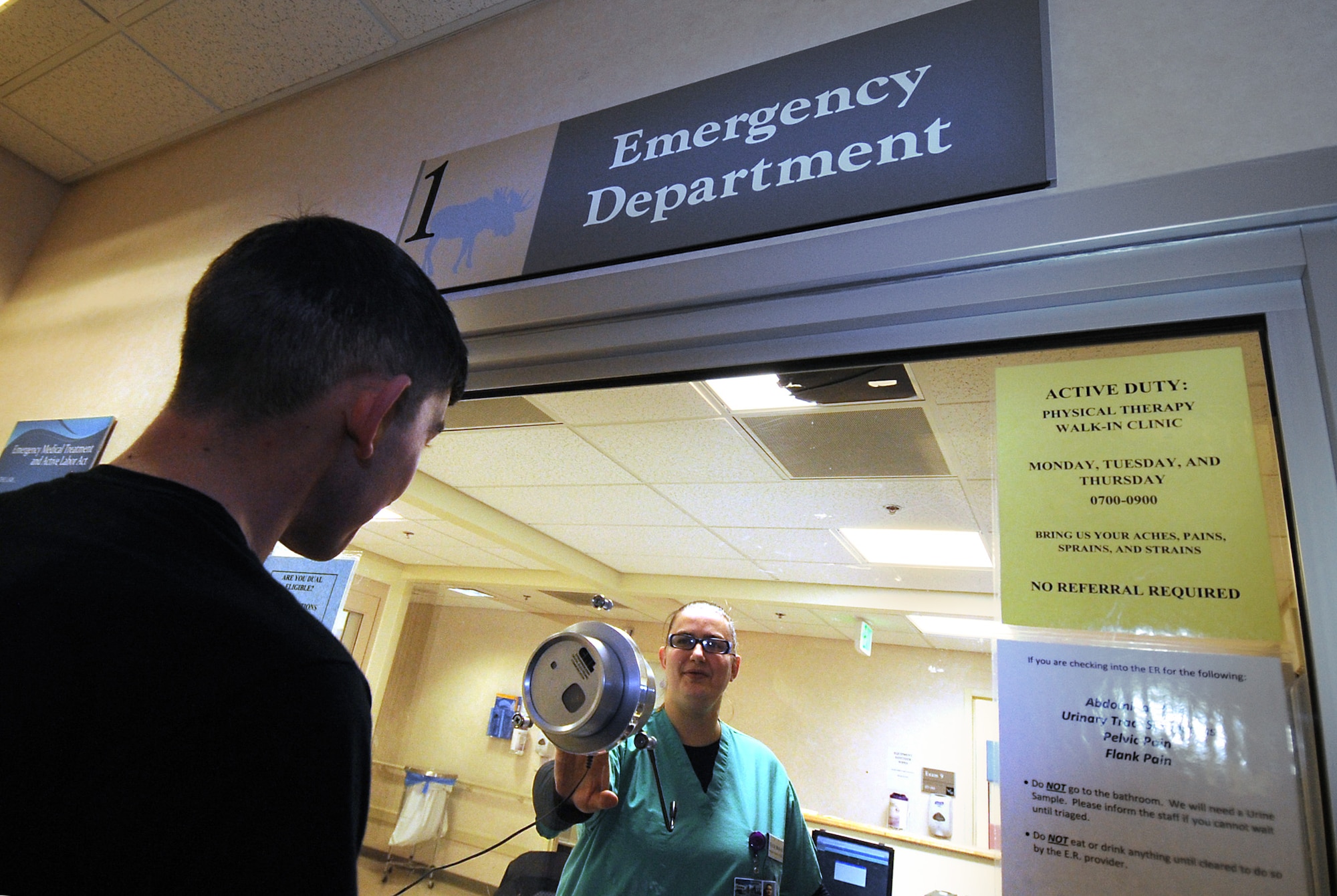 Cecila Meyers demonstrates helping a patient at the check-in window of the emergency room Dec. 8. The ER has many capabilities to serve patients from scraped knees to trauma stabilization. Knowing the difference between emergency and non-urgent needs can help you receive the best care for your situation. Meyers is a medical technician with the 673d Medical Operations Squadron. (U.S. Air Force photo/Staff Sgt. Cynthia Spalding)