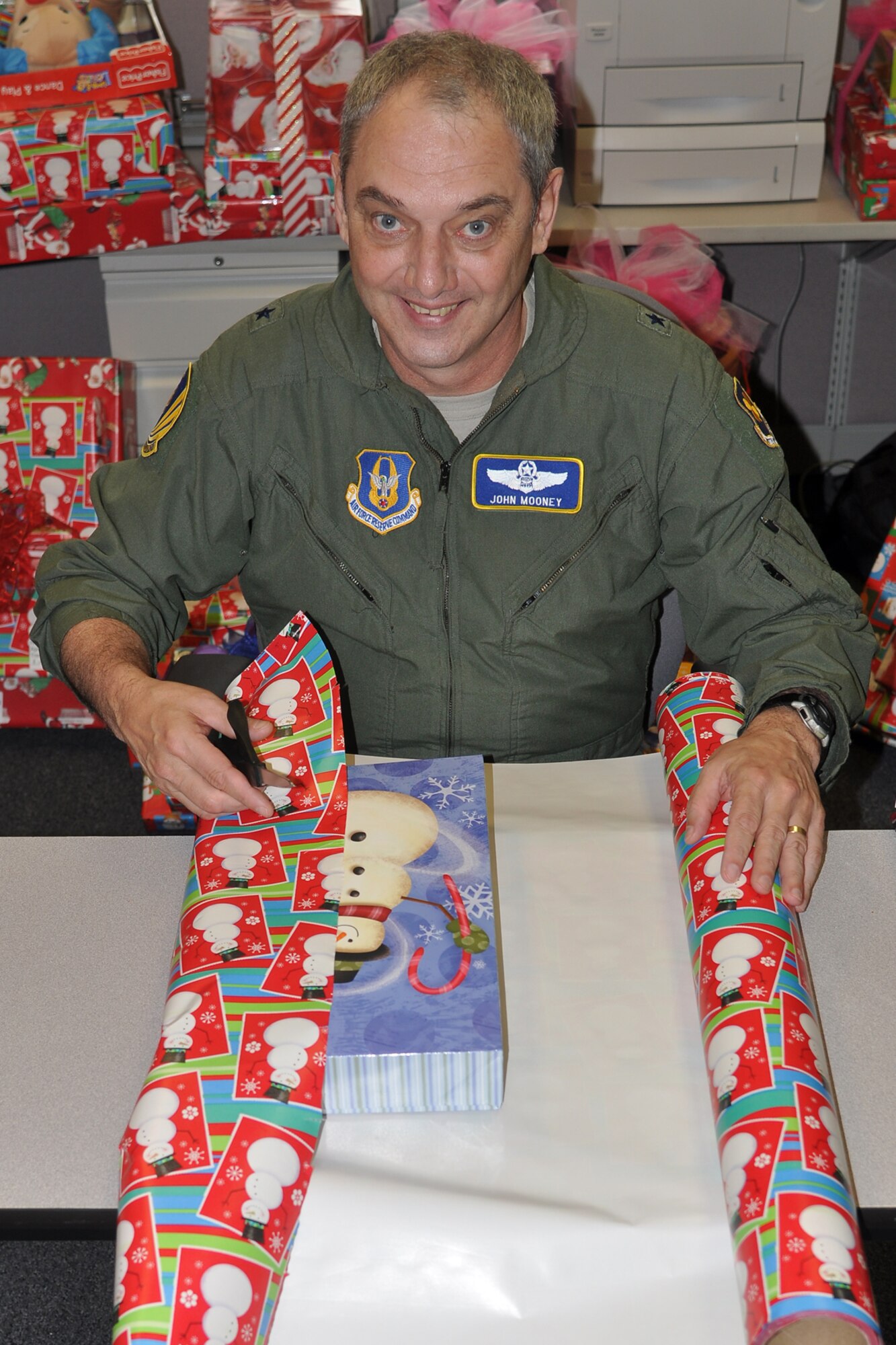 Brig. Gen. John J. Mooney III, the commander of the 307th Bomb Wing, navigates his way around a present wrapping mission at the headquarters building on Barksdale Air Force Base, La., Dec. 14, 2011. Mooney was supporting the Santas in Blue program, which is an annual event for Barksdale Airmen, and helps local foster care children celebrate the holiday season. (U.S. Air Force photo by Betty Stephens/Released)