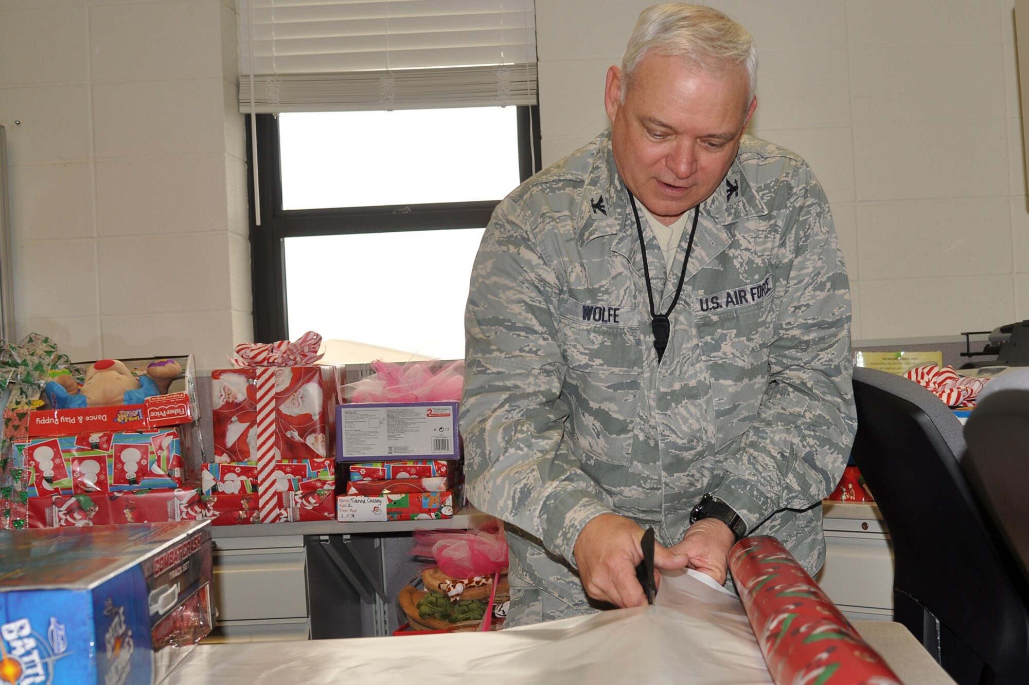 Col. Kevin Wolfe, the commander of the 307th Mission Support Group, is in deep concentration as he makes a straight cut while wrapping a present at the headquarters building on Barksdale Air Force Base, La., Dec. 14, 2011. Wolfe was supporting the Santas in Blue program, which is an annual event for Barksdale Airmen, and helps local foster care children celebrate the holiday season. (U.S. Air Force photo by Betty Stephens/Released)