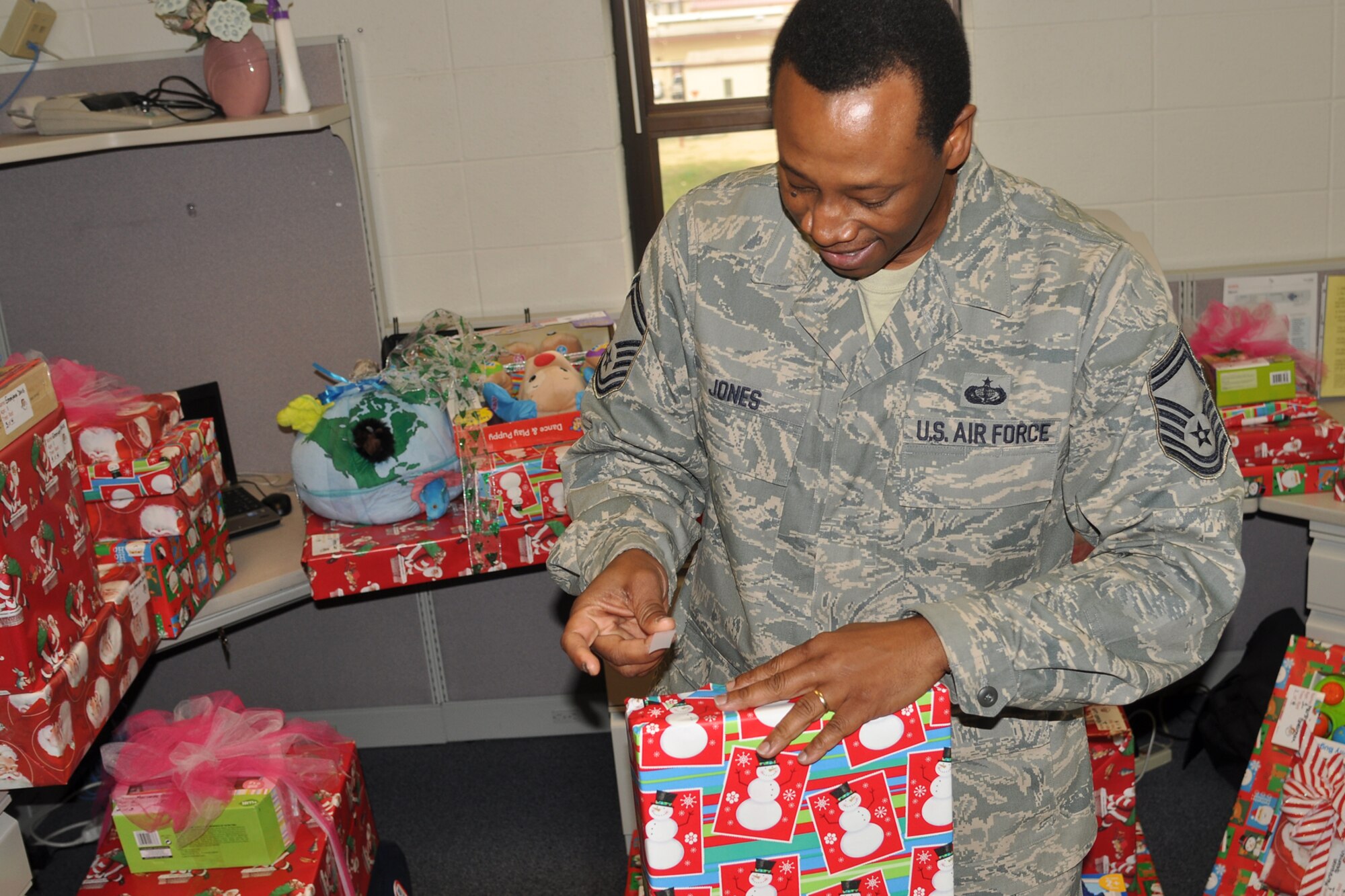 Senior Master Sgt. William Jones, the senior recruiter for the 307th Bomb Wing, puts the final piece of tape on a present at the headquarters building on Barksdale Air Force Base, La., Dec. 14, 2011. Jones was supporting the Santas in Blue program, which is an annual event for Barksdale Airmen, and helps local foster care children celebrate the holiday season. (U.S. Air Force photo by Betty Stephens/Released)