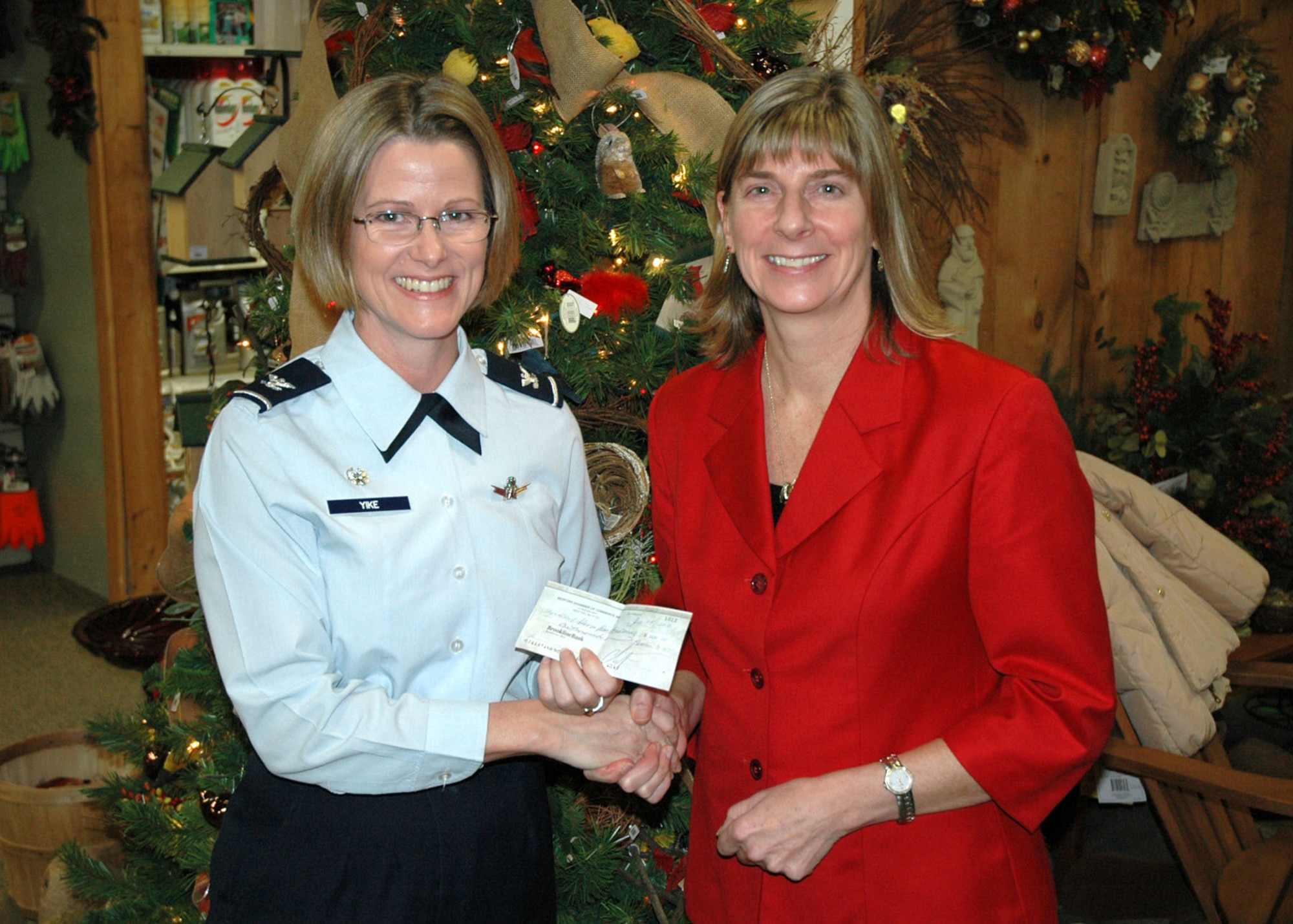 BEDFORD, Mass. - Outgoing Bedford Chamber of Commerce President Pam Brown presents Col. Stacy L. Yike, 66th Air Base Group commander, a check for $1,000
for the Hanscom Heroes fund during the chamber's annual holiday party Dec. 14.  Each year, part of the proceeds raised by the chamber through their "Flavors Of
Bedford" event are donated to the base. (U.S. Air Force photo by J.C. Corcoran)
