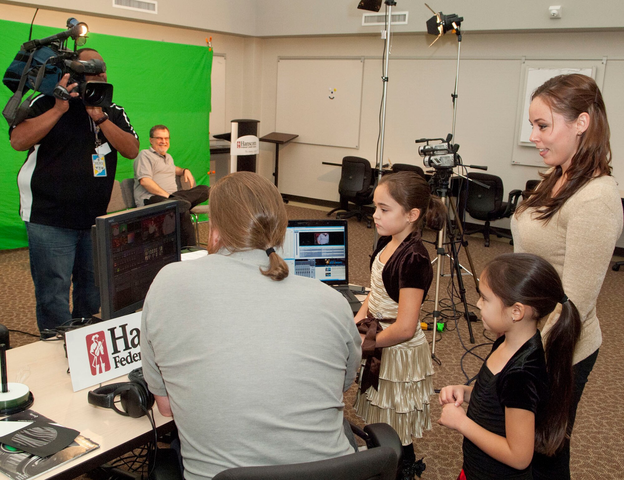 HANSCOM AIR FORCE BASE, Mass. -- Tiffany Hagler and her two daughters, Kaylie and Madison, prepare to record a holiday greeting with the help of Kevin Mann (sitting at computer) from Operation Best Wishes for her deployed husband, Army Sgt. Sheridan Hagler, at the Hanscom Federal Credit Union on Dec 7. Ralph Griswold (with camera), from WBZ-TV, was also on hand to speak to family members of deployed personnel. Operation Best Wishes is an annual campaign held during the holiday season to help military families stay connected in a very memorable way. (U.S. Air Force photo by Mark Wyatt)