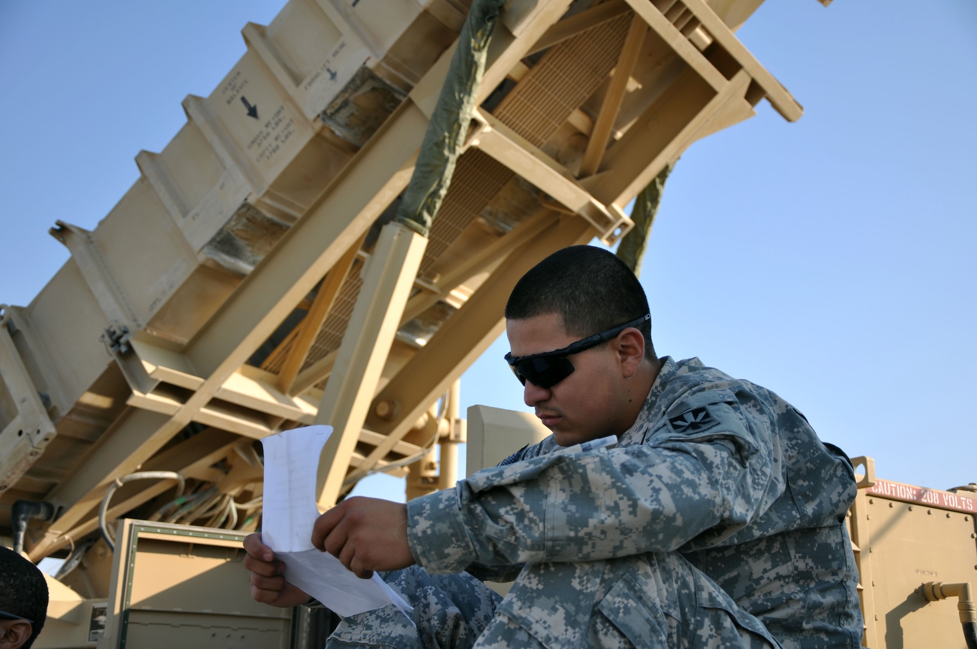 U.S. Army Spc. Andrew Badillo, reviews his notes while sitting on the base of an MIM-104 Patriot surface-to-air missile battery during the 2011 Flightline Fest at an undisclosed location in Southwest Asia Dec. 15, 2011.The 379th Air Expeditionary Wing hosts the annual event to offer service members the opportunity to examine first-hand the aircraft that execute the wing's expeditionary mission. Various units from the wing as well as units from coalition partners put on demonstrations and displays to educate people on how they cooperate with each other to accomplish the mission.  (U.S. Air Force photo/Senior Airman Michael Charles)