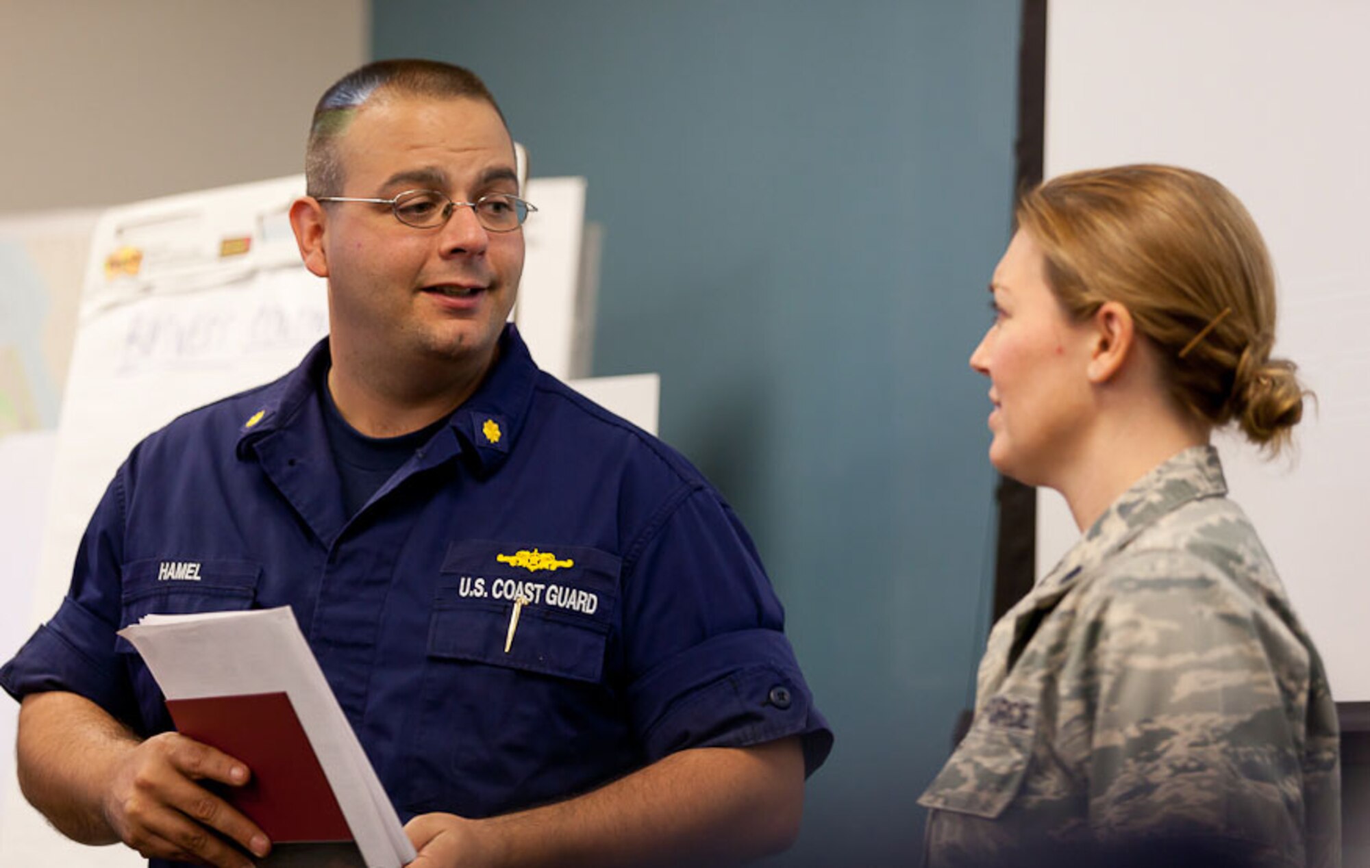 Lt. Col. Valerie Hackett of the Electronic Systems Center Capabilities Integration Office discusses proof of concept capability with Lt. Cmdr. Ryan Hamel, 1st Coast Guard District, at the Logan Airport Emergency Operation Center Oct. 6. Hamel and Hackett were members of a team that demonstrated a “mesh network” capability that enables the sharing of information between disparate command centers and mobile tactical assets in real-time. (Courtesy photo)