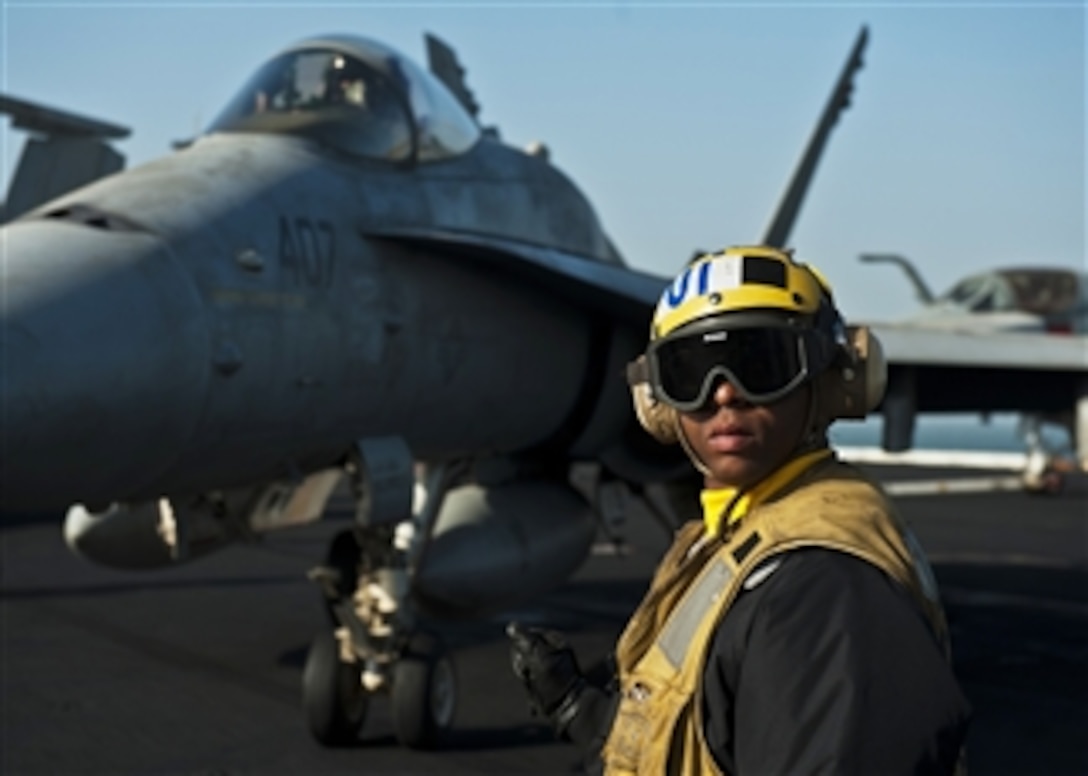 U.S. Navy Petty Officer 1st Class Brian Adams checks for a clear deck aboard the aircraft carrier USS John C. Stennis (CVN 74) in the Persian Gulf on Dec. 12, 2011.  The John C. Stennis deployed to the U.S. 5th Fleet area of responsibility to conduct maritime security operations and support missions as part of Operations Enduring Freedom and New Dawn.  