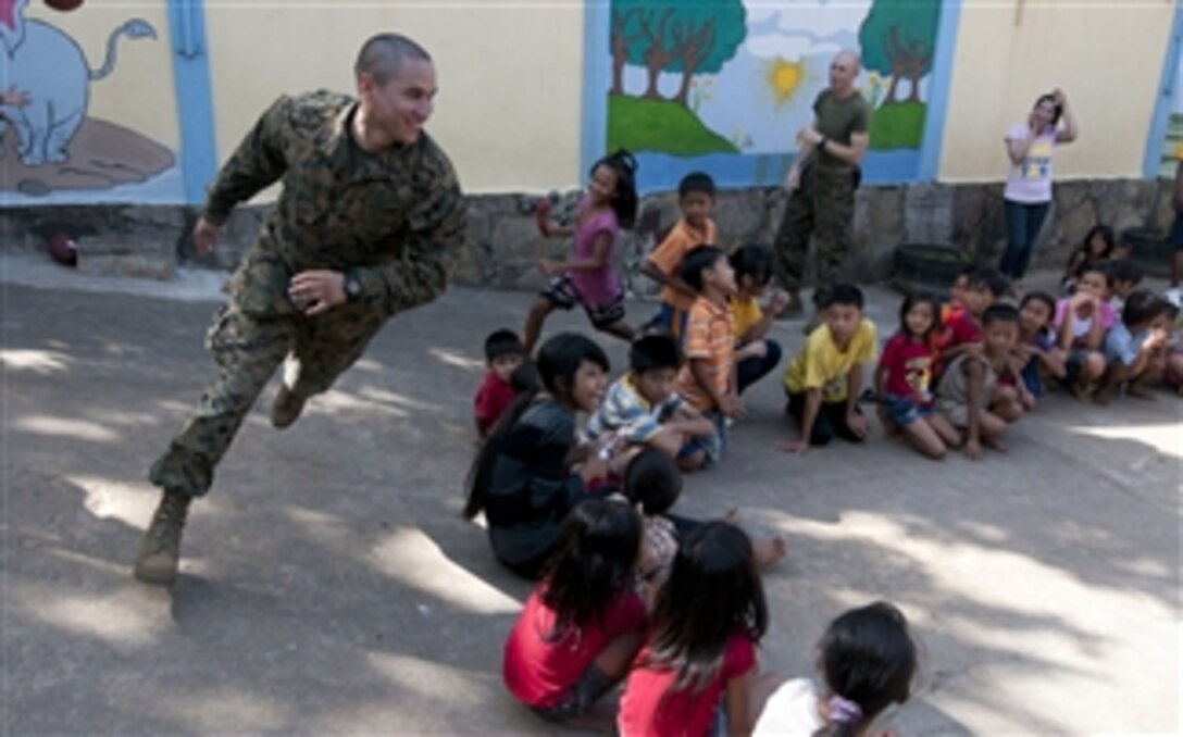 Sgt. Marcos Bustos, assigned to the 11th Marine Expeditionary Unit embarked aboard the amphibious dock landing ship USS Pearl Harbor (LSD 52), plays with children during a community service event at the Help the Cambodian Children Goodwill Center in Sihanoukville, Cambodia, on Dec. 14, 2011.  The 11th Marine Expeditionary Unit is deployed to the U.S. 7th Fleet area of responsibility with the Makin Island Amphibious Ready Group.  
